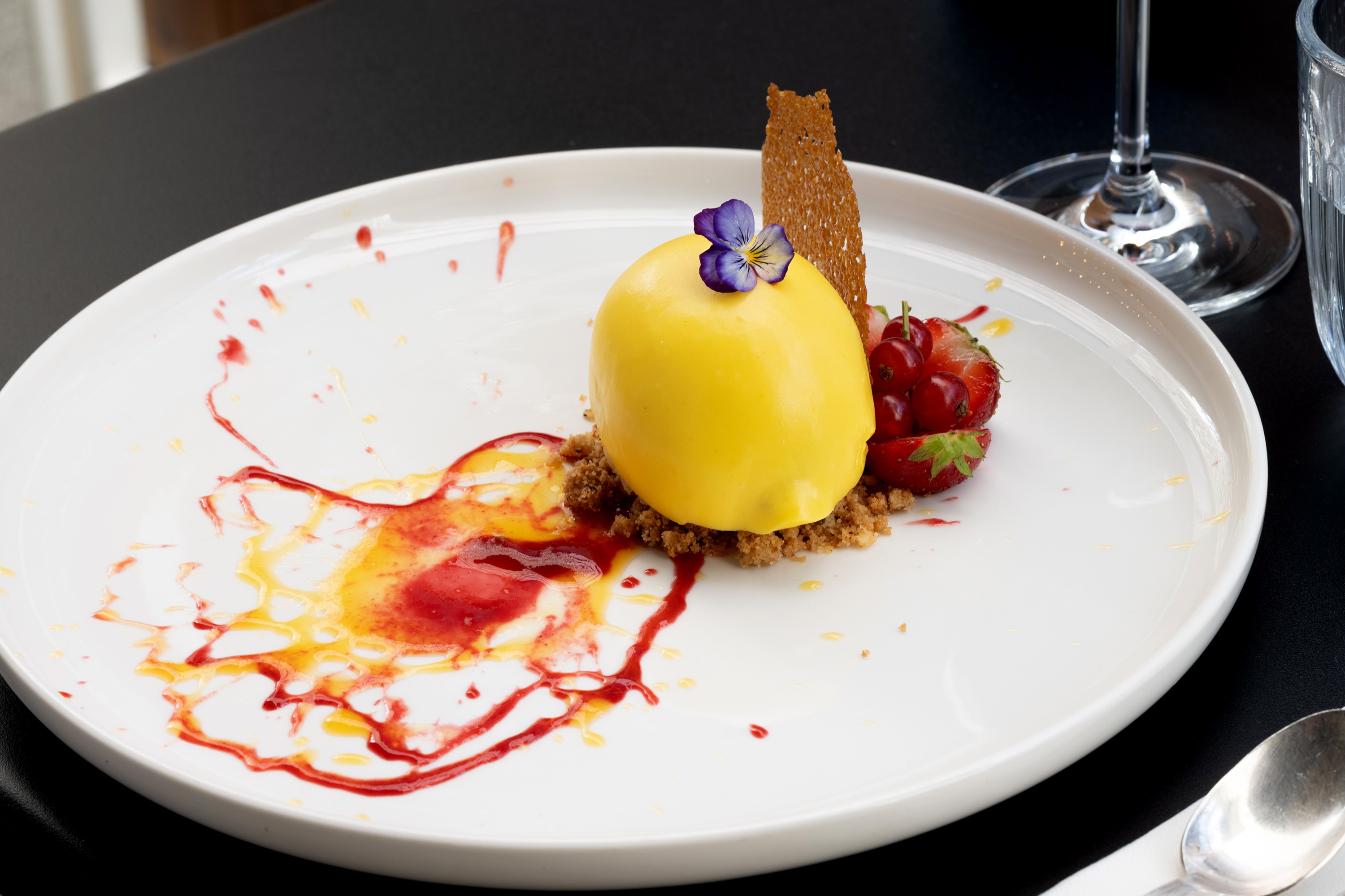 a glass of cocktail with a slime orange fruit