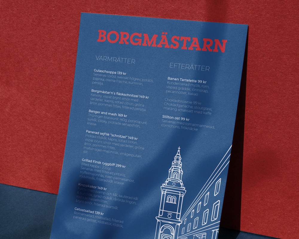 A navy blue Borgmästarn branded folder or menu with illustrated details laid on a deep red surface, demonstrating the print identity system.