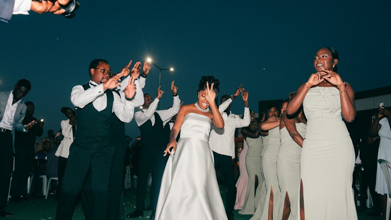 Bride and guests dancing outdoors at night lit by flash