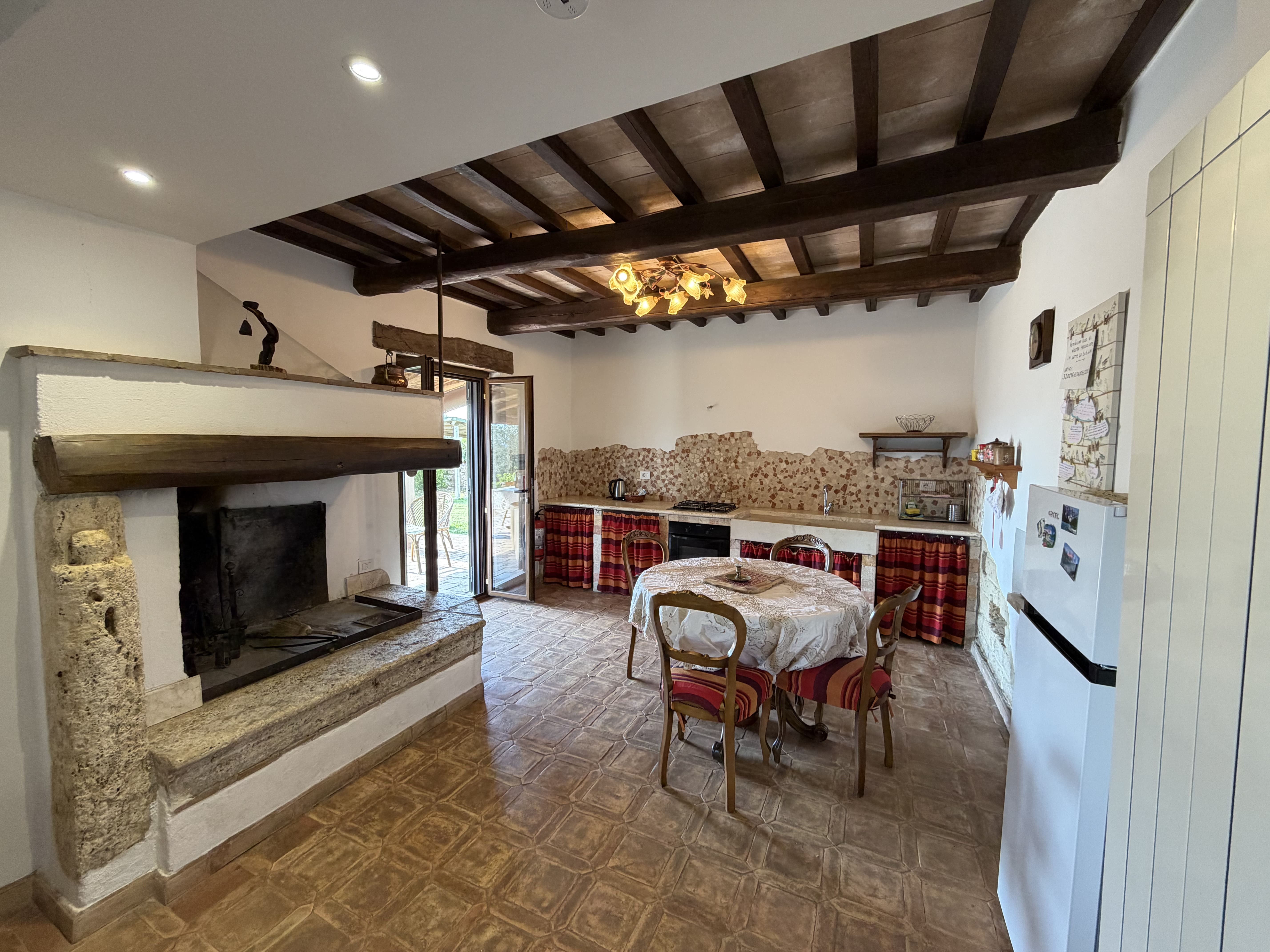 Living room with stone fireplace and wide opening onto the green countryside, house in Pitigliano