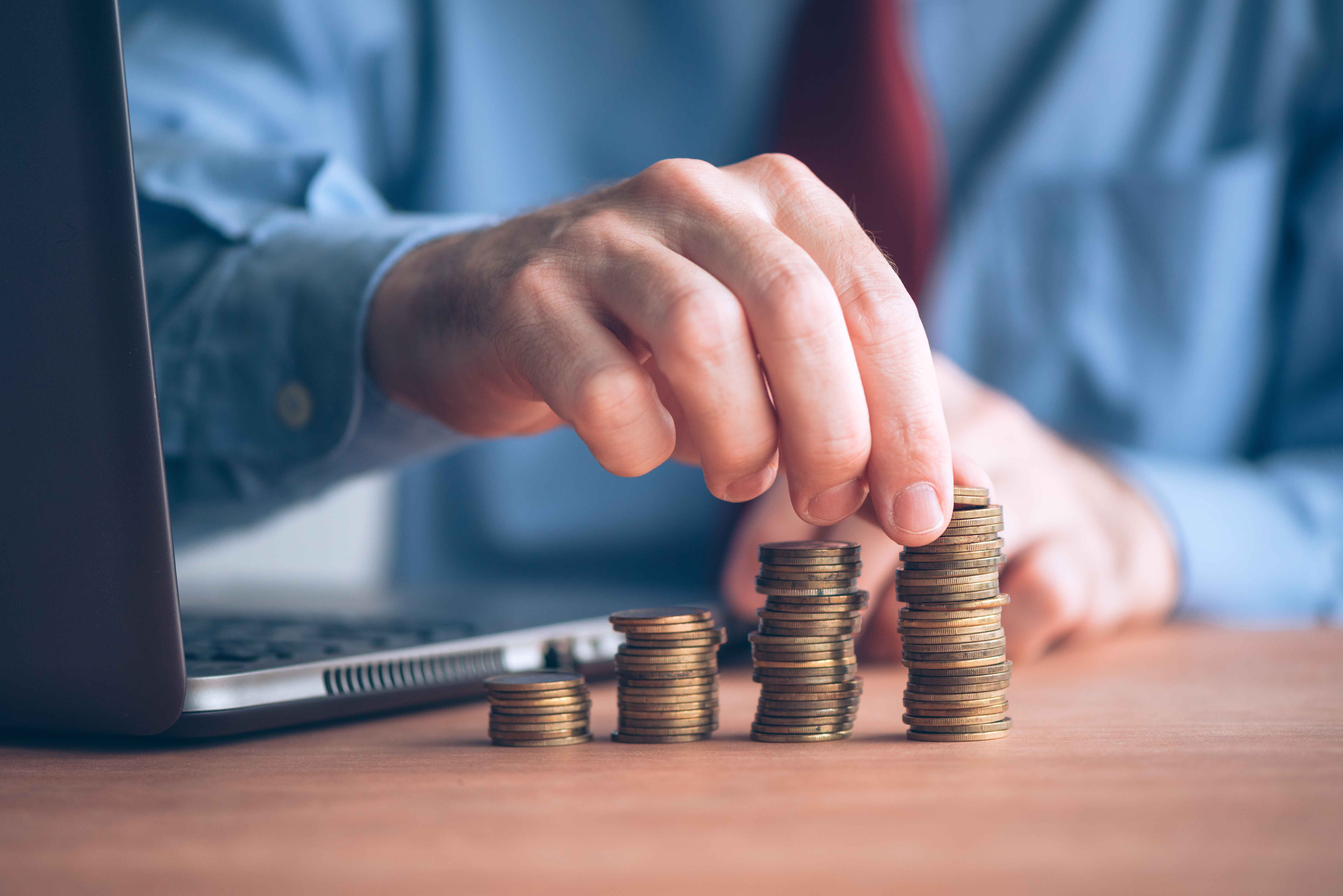 Mann stapelt Münzen - Symbolbild für den Finanzsektor