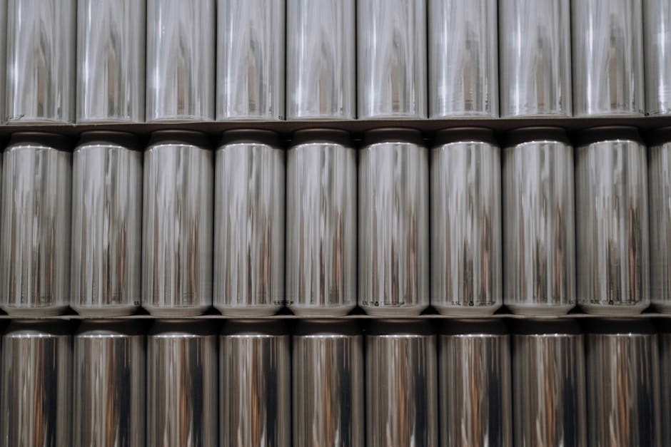A neatly organized stack of reflective aluminum beverage cans in an industrial setting.
