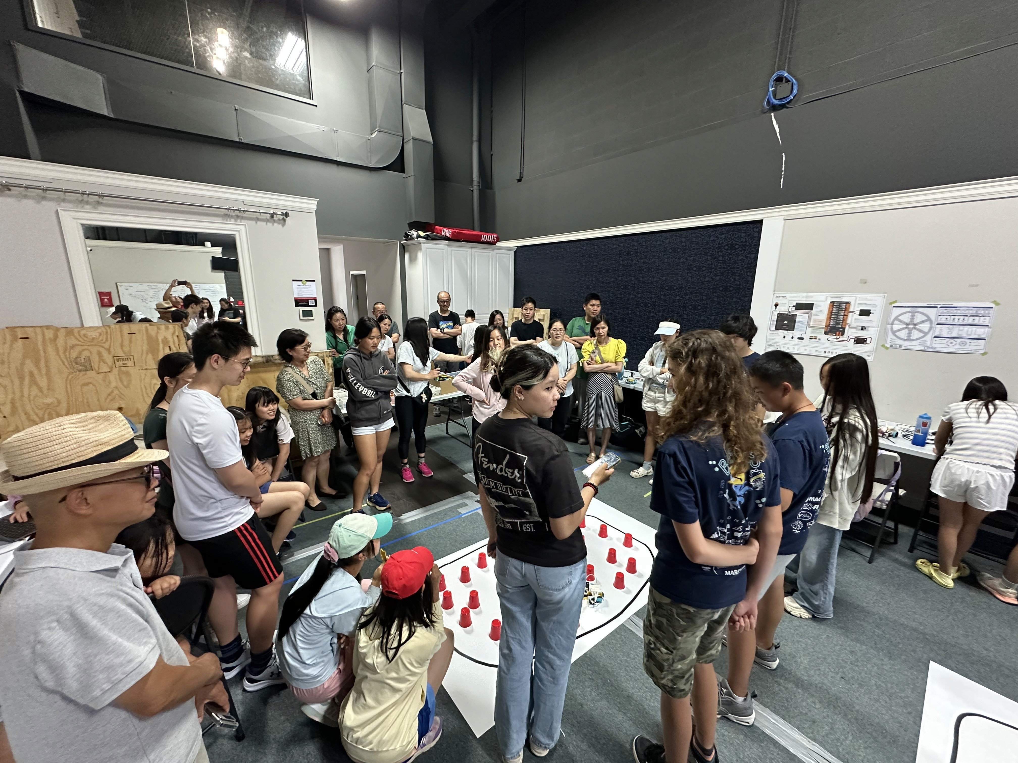Parents of campers celebrate and watch the cup contest using robots and knowledge that they learned at Solversmind Robotics studio.