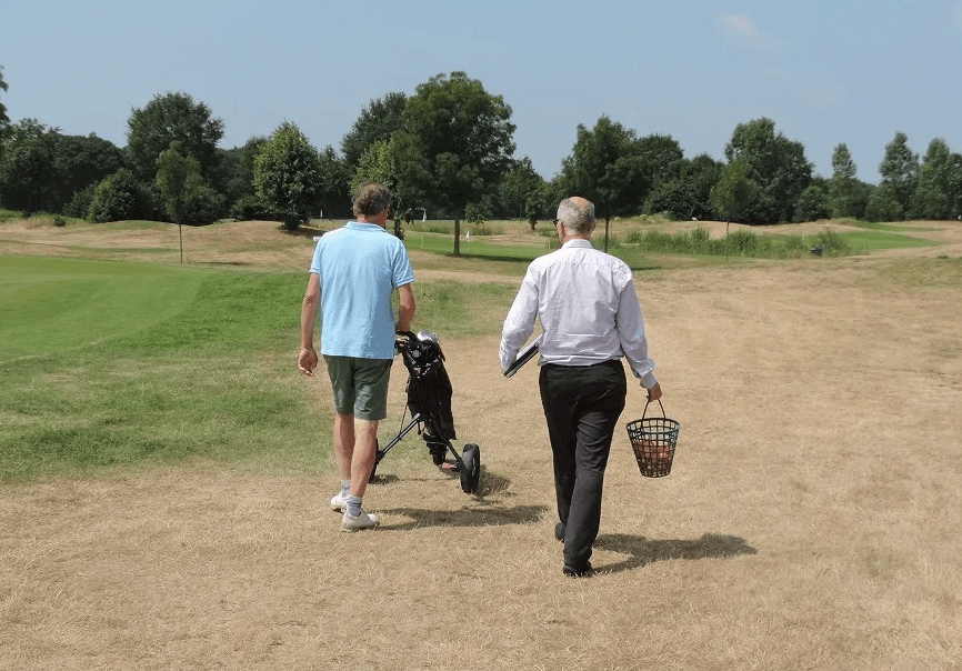 Foto van Mark Theelen en cliënt die op golfbaan lopen bij een training in succesversnelling