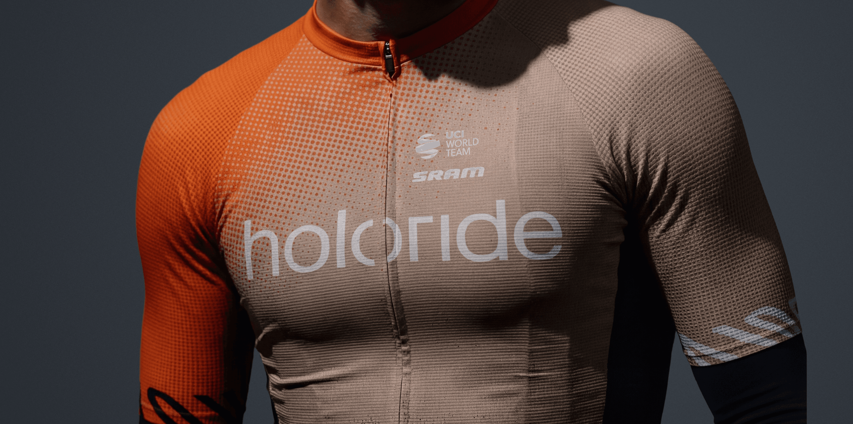 Holoride cyclist wearing a holoride helmet and branded jersey on a dark grey studio backdrop.