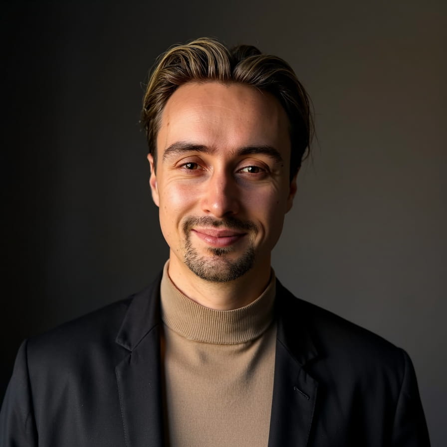 Smiling man in black shirt against gray background.