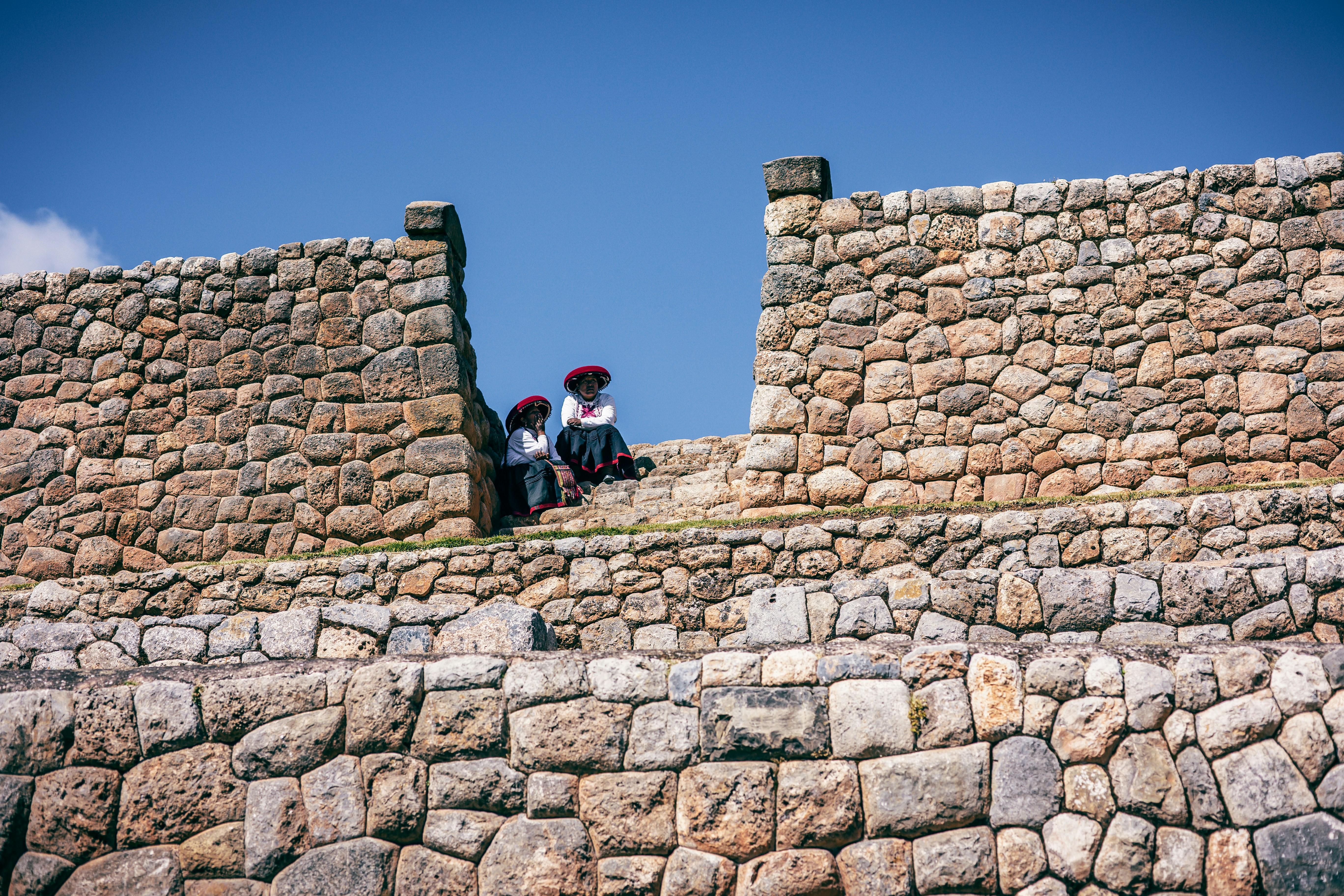 a couple of people sitting on top of a stone wall