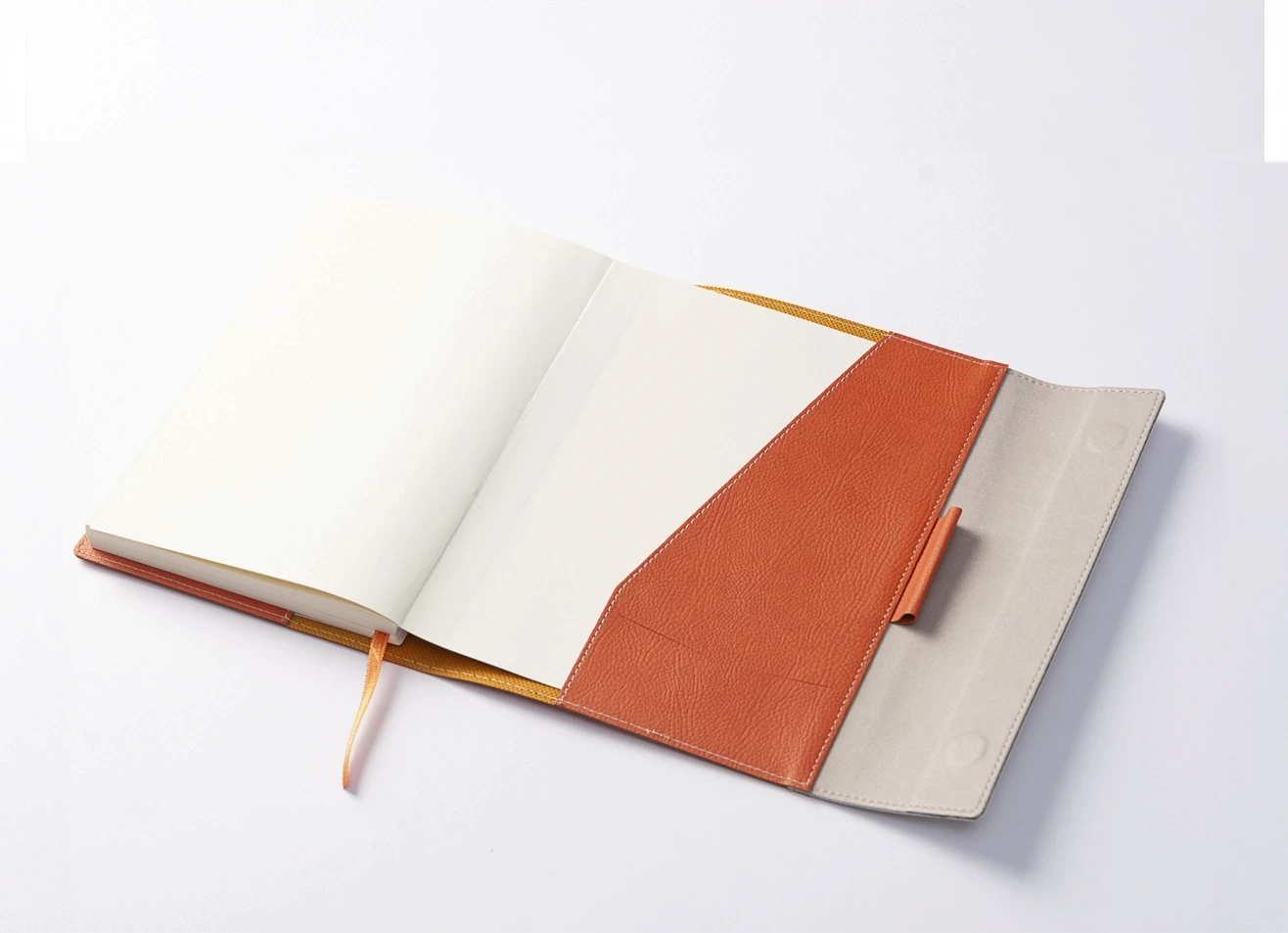 Flat lay of open two-tone leather journal with blank ivory pages and ribbon bookmark