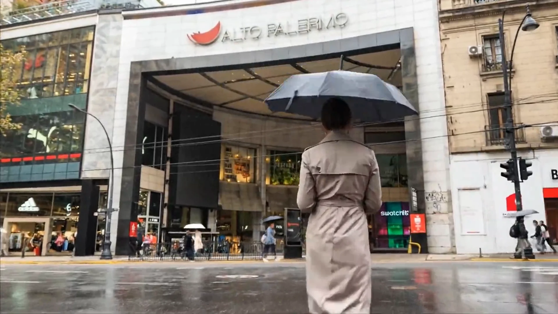 Mujer con paraguas frente a la entrada de Alto Palermo en un día de lluvia