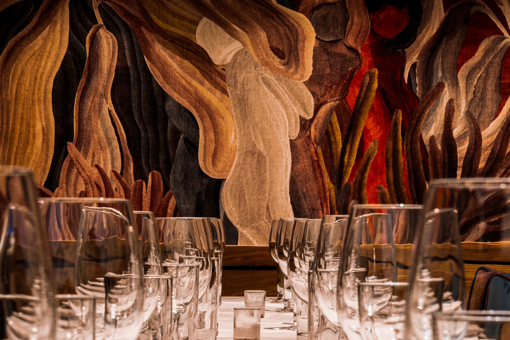 Glasses lined up in a row with artwork in the background