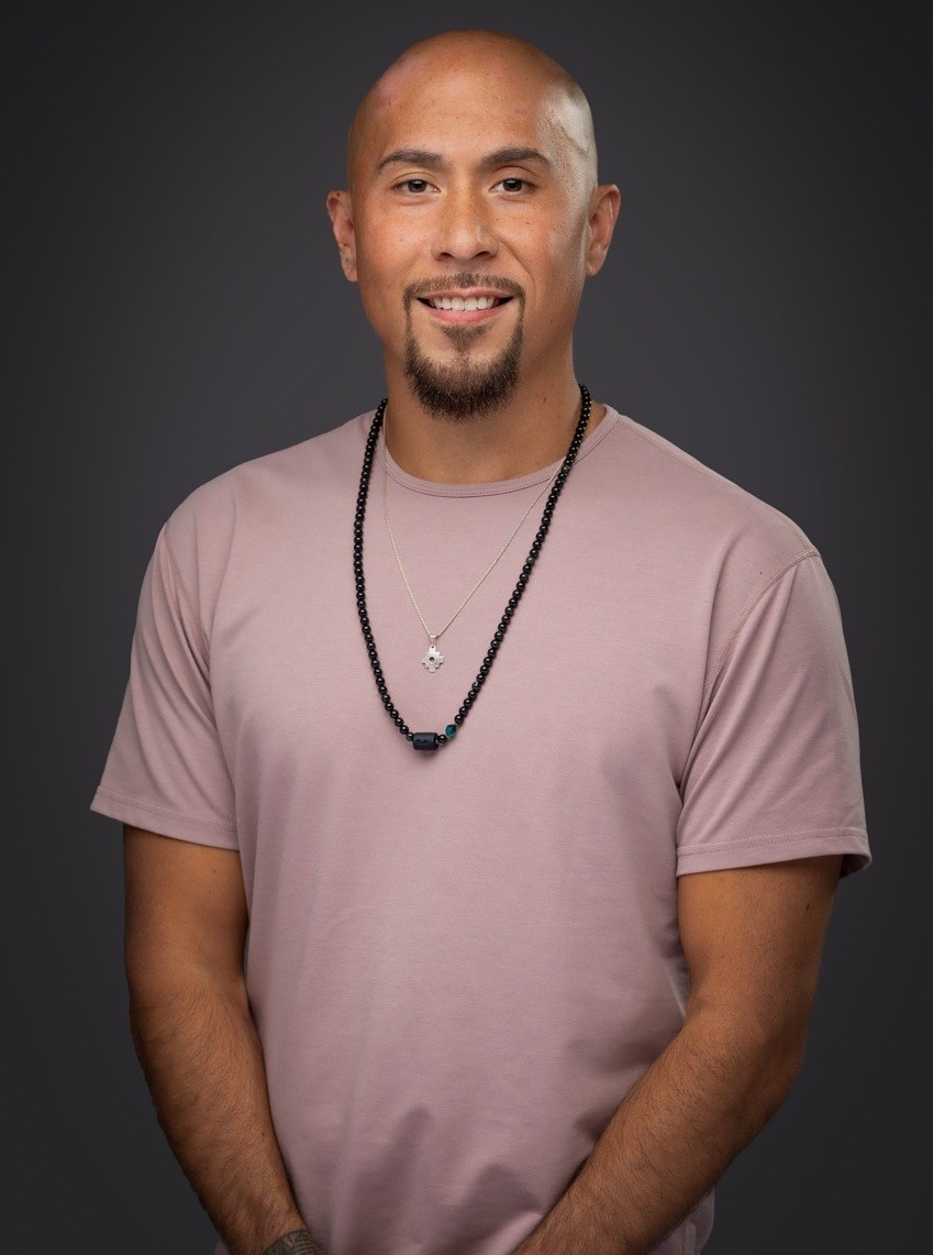 Experienced massage therapist and personal trainer standing in a serene studio with soft lighting
