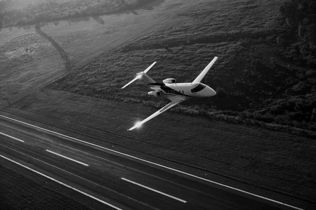 Aerial view of a small aircraft flying over a landscape with visible geometric fields below.