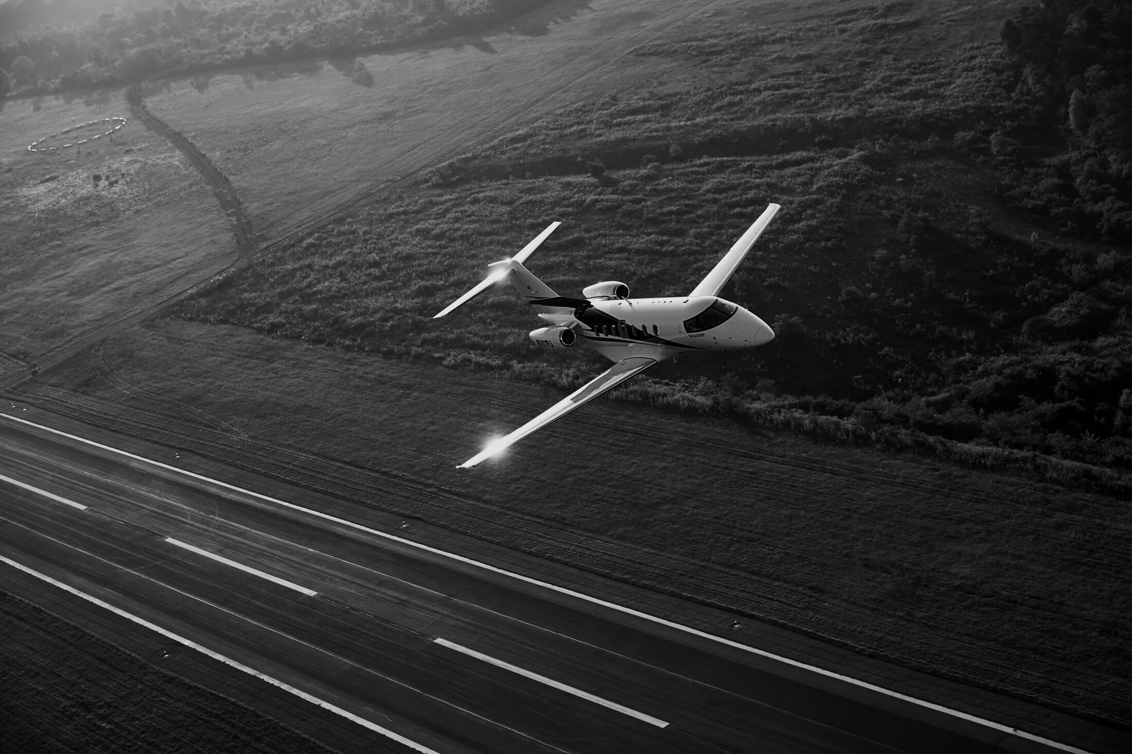 Aerial view of a small aircraft flying over a landscape with visible geometric fields below.
