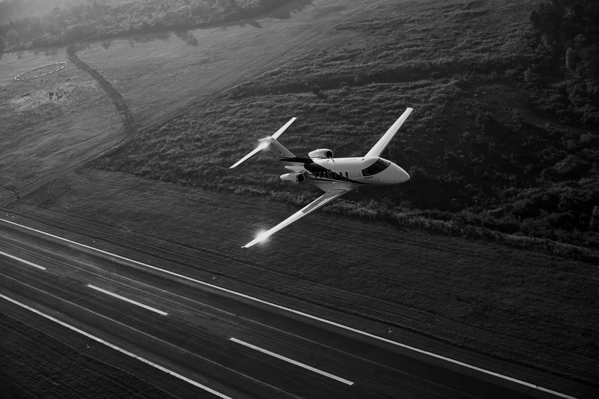Aerial view of a small aircraft flying over a landscape with visible geometric fields below.