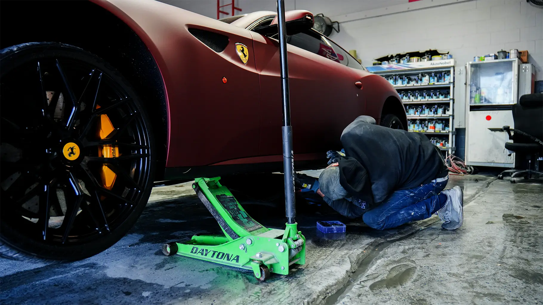 Auto body shop technician servicing a Ferrari during professional collision repair.