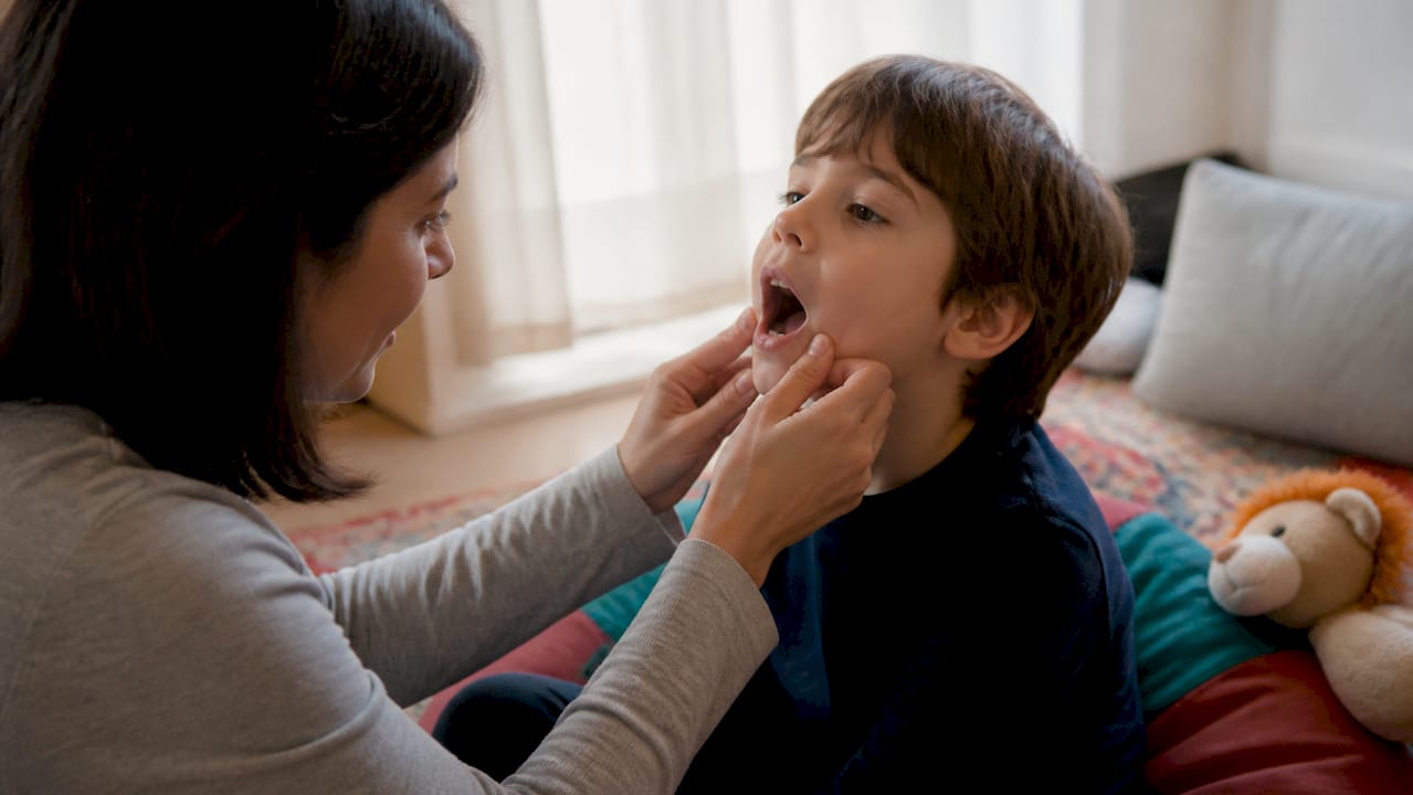 Caregiver helping an autistic child practice opening their mouth before a dentist visit