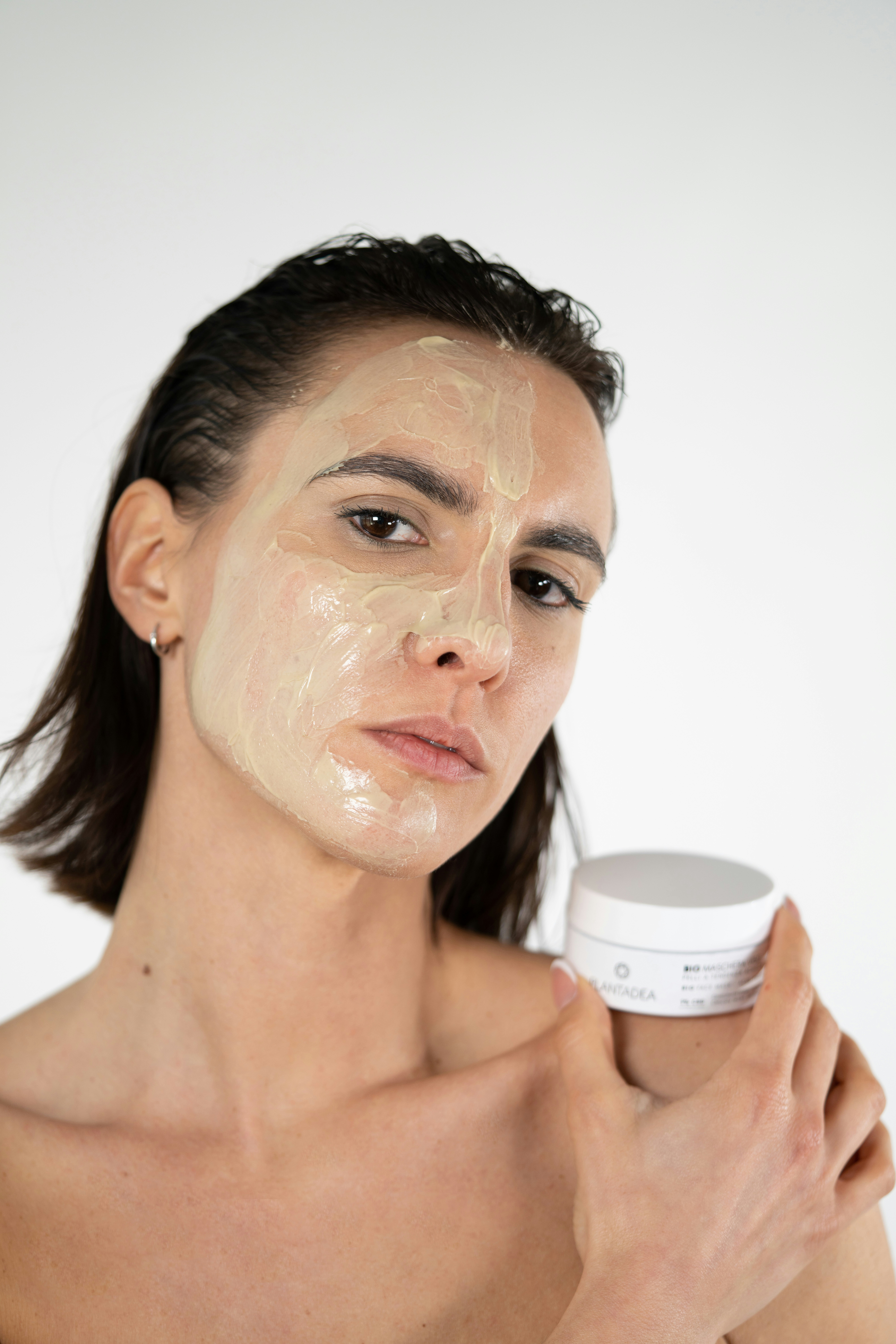 a woman holding a jar of cream on her face