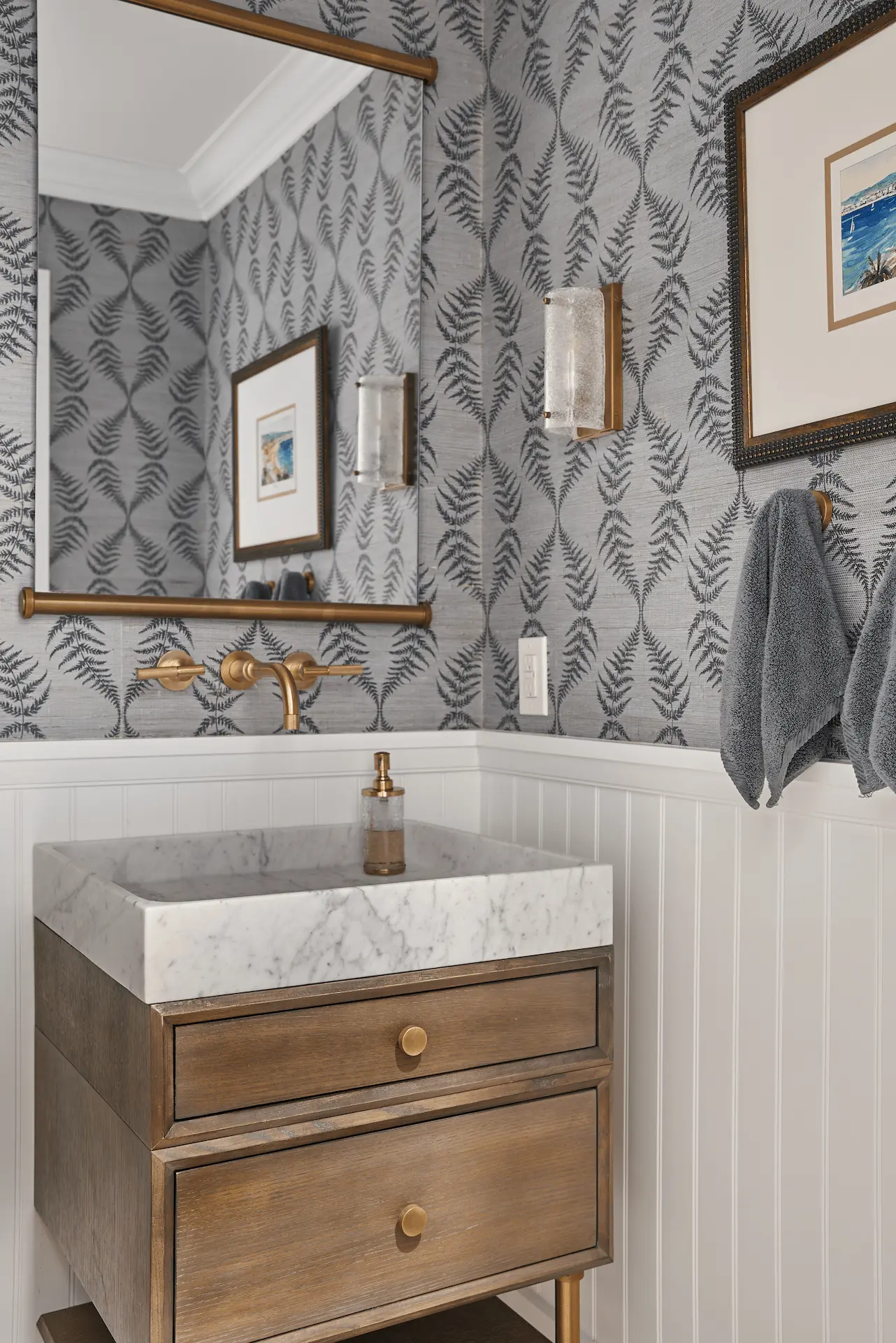 Portrait of the powder bathroom vanity, featuring wainscot and patterned wallpaper, adding a touch of sophistication in the Ladera Ranch Remodel. Photo by Todd Huge.