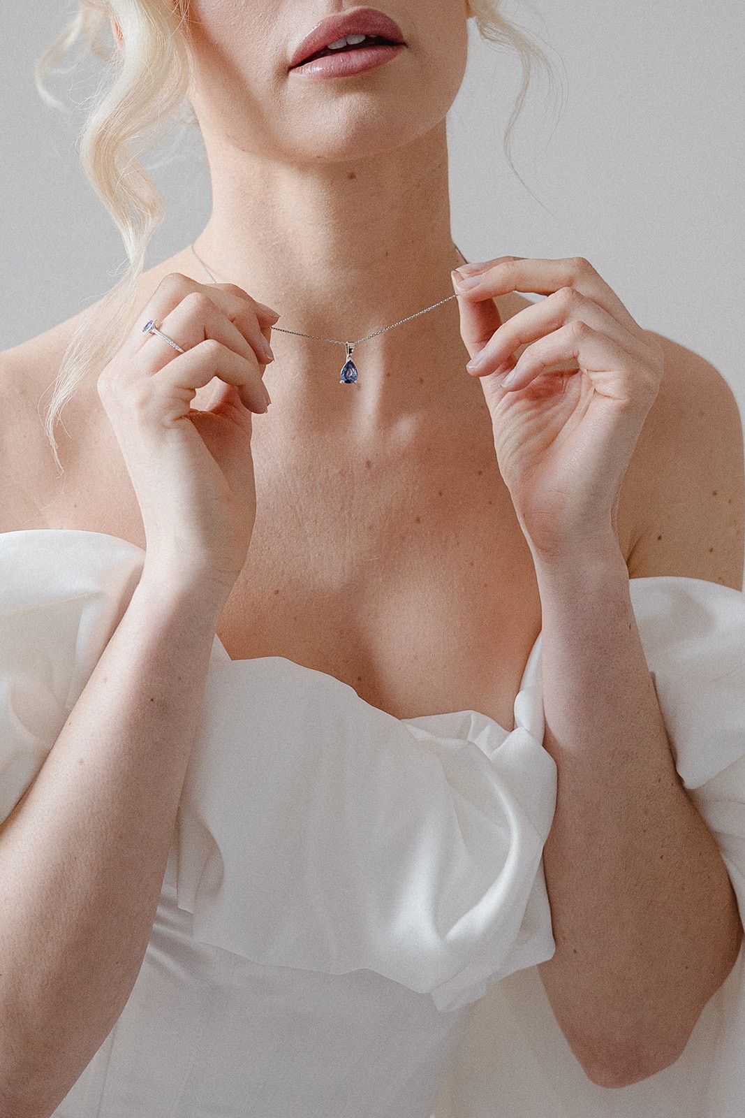 A bride in a lace wedding dress gently holds.
