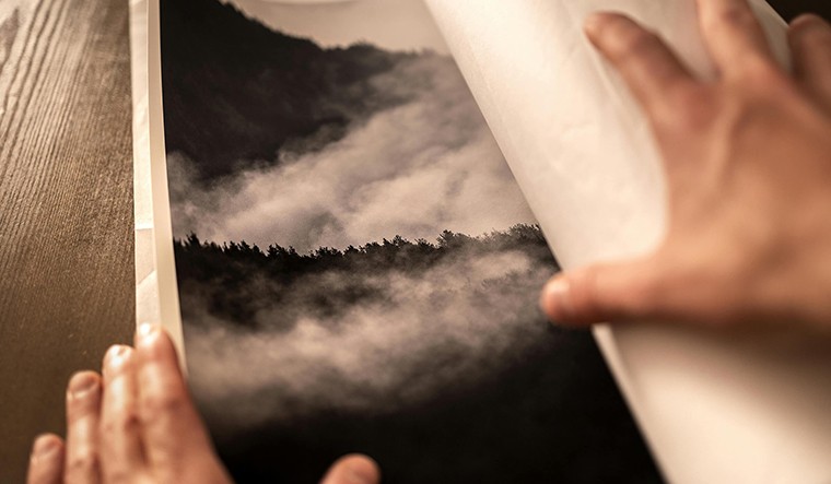 Ręce zawijające czarno-biały wydruk przedstawiający górski krajobraz z lasem – przykład pracy na papierze FineArt