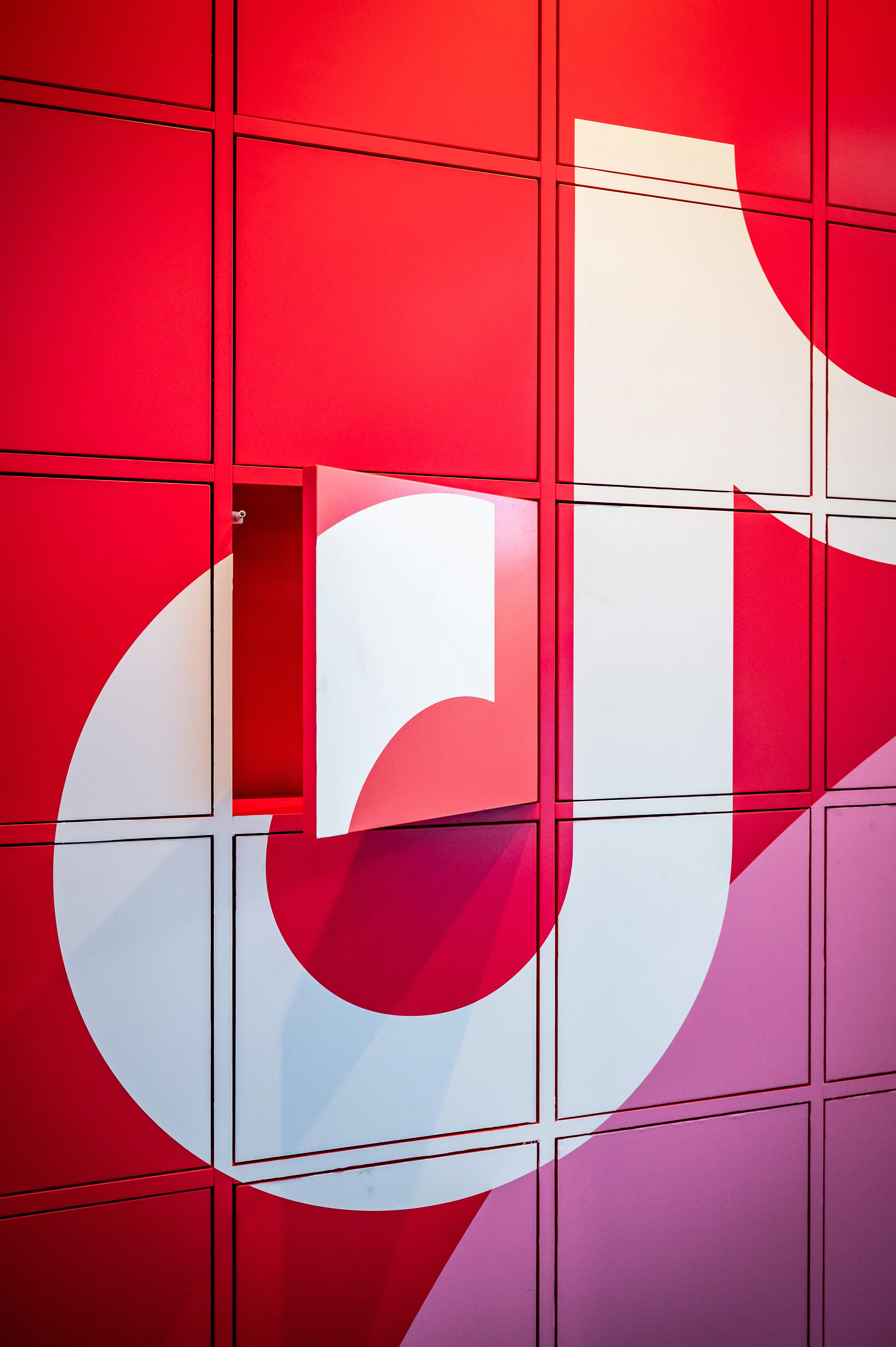 Red locker wall with oversized white TikTok logo and one open door at the TikTok OMR booth.