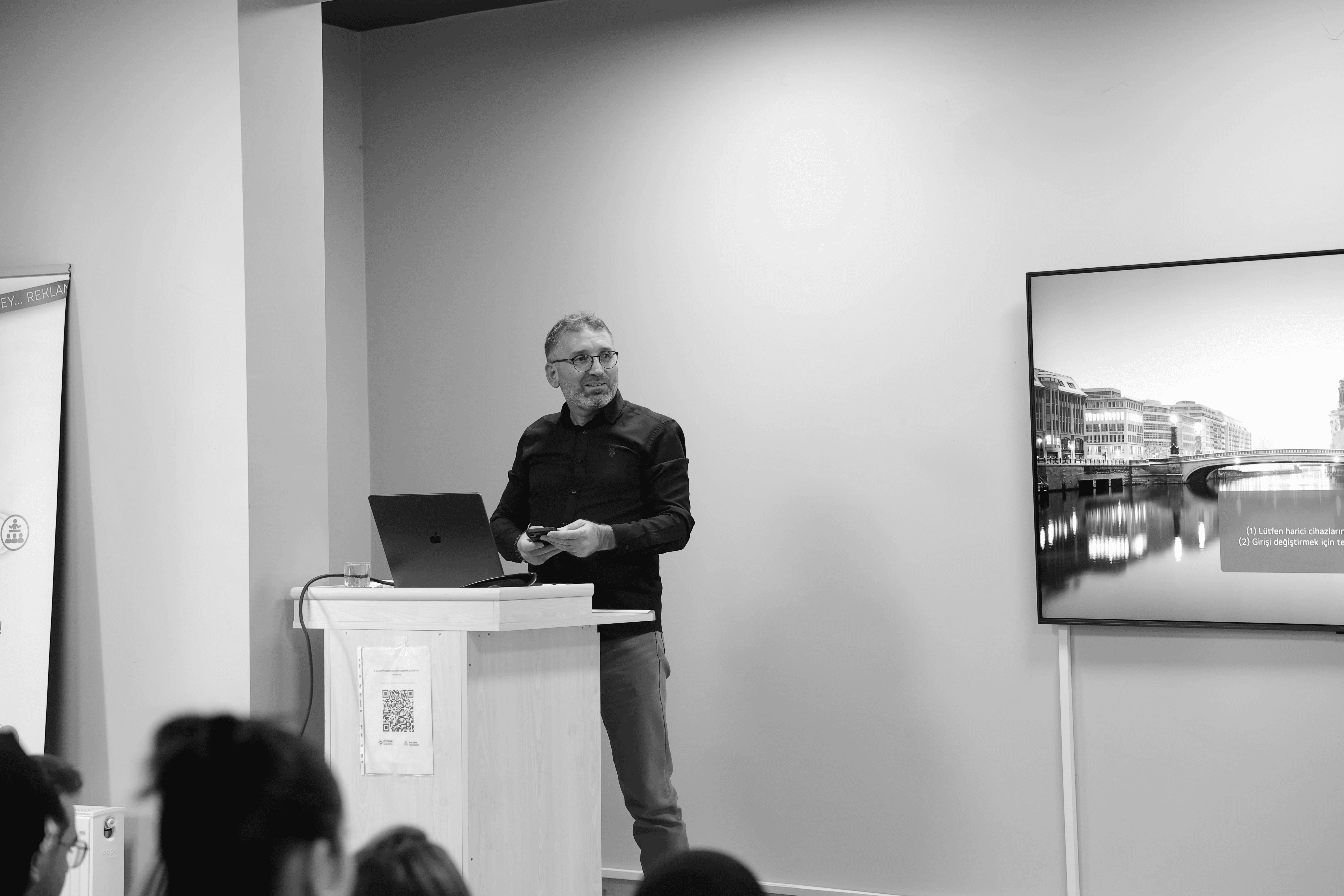 Four people engage in conversation in front of a wall with text, all smiling and interacting in a casual setting.