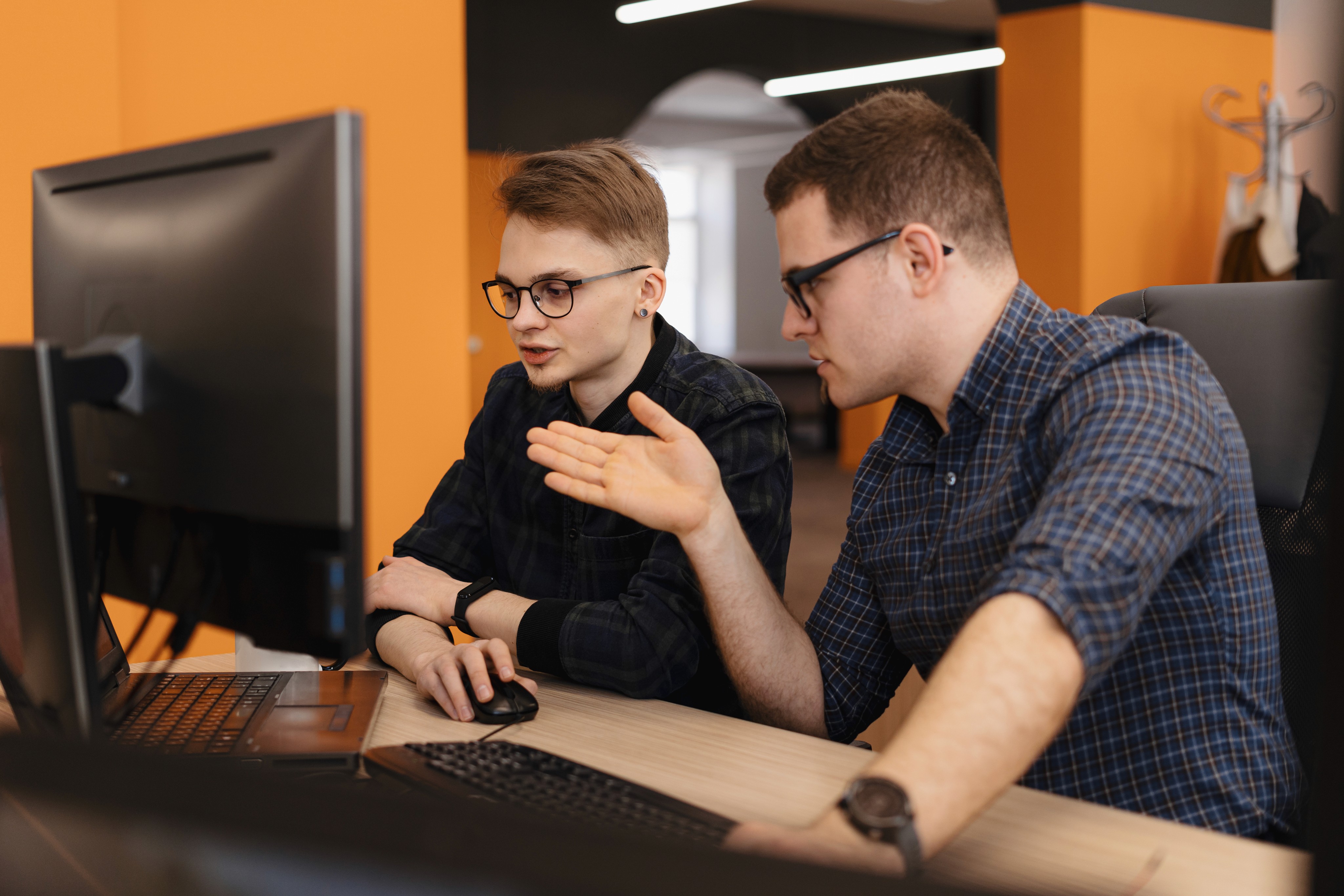 Three coworkers talking around a laptop in a café.