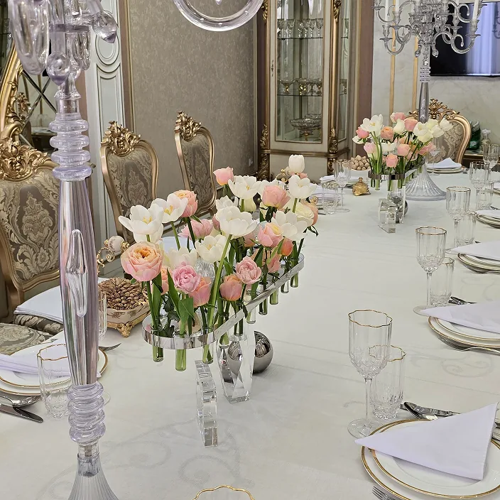 Elegant diningtable withgold-rimmed platestulip and rose centerpieces, crystalglassware and ornategold chairs in a luxurious setting