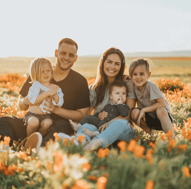 Family of 5 sitting in a sunny field