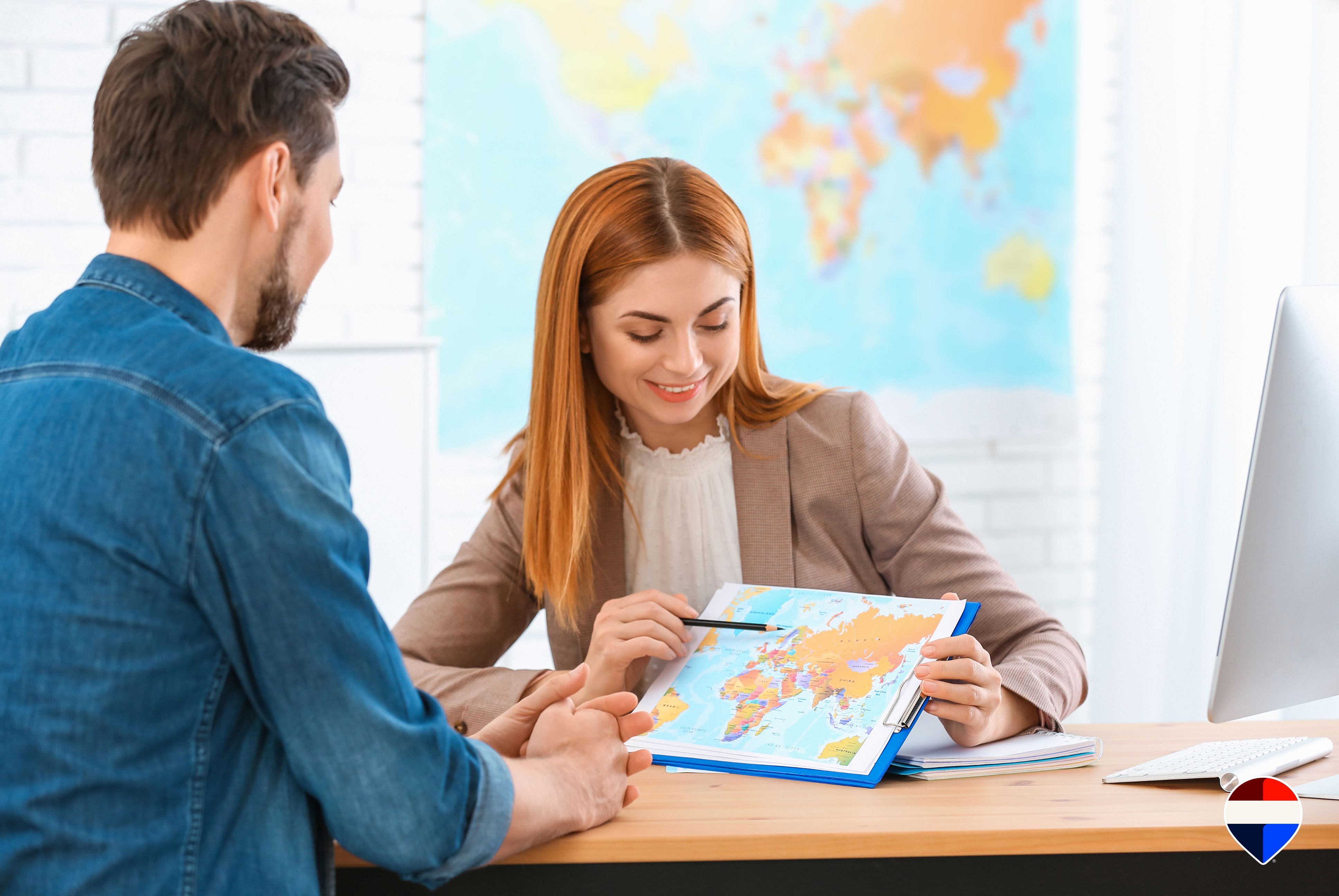 Agente immobiliare che illustra a un cliente la rete internazionale di contatti davanti a una mappa del mondo