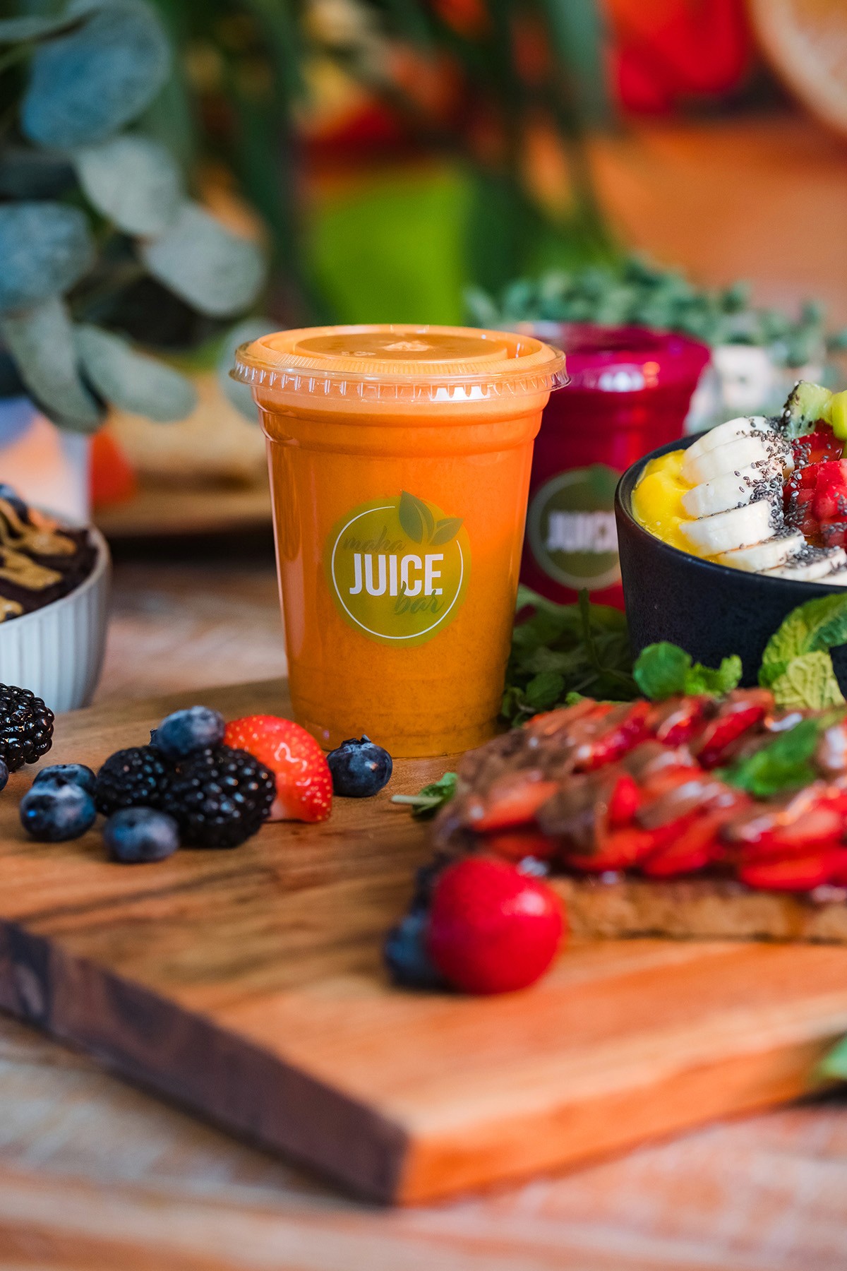 Orange Maha smoothie surrounded by fruit