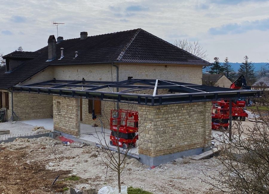 Rénovation d’un bâtiment en pierre avec installation d’une charpente métallique en cours.