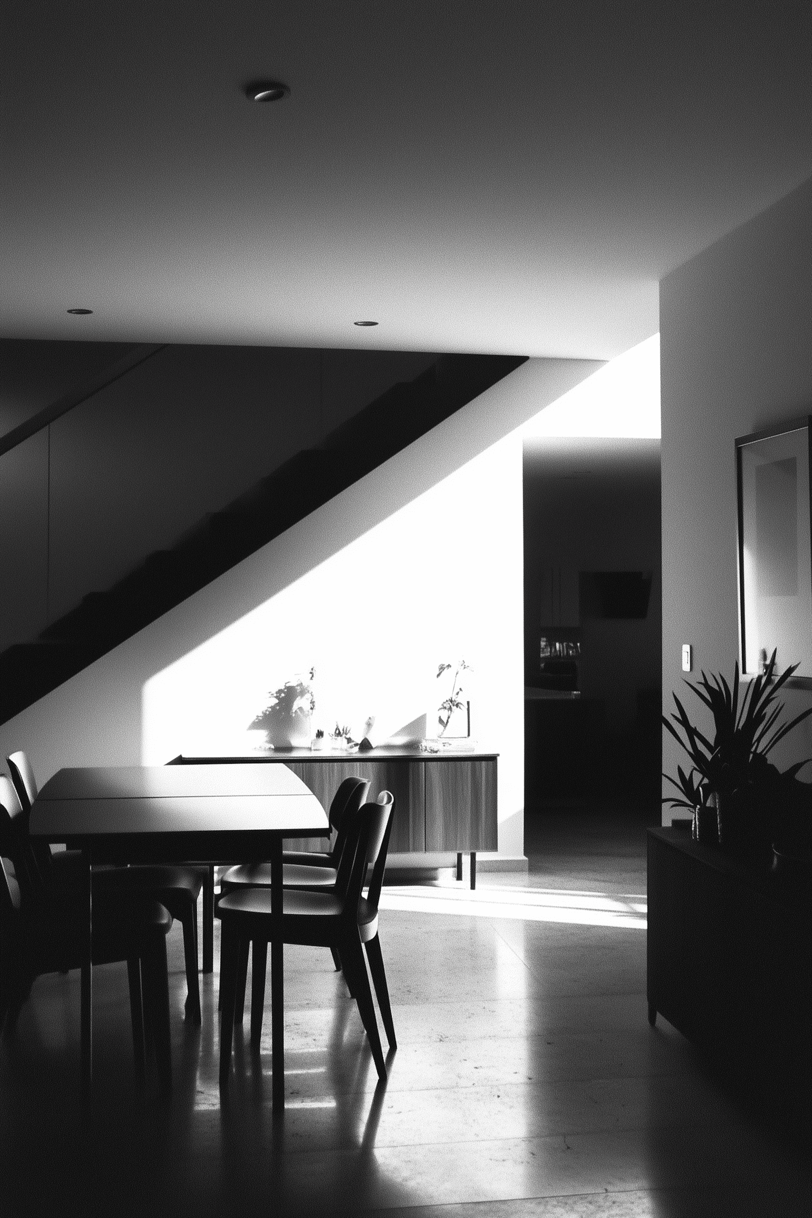 Sunlit dining space with wooden cabinetry, clean lines, modern table and chairs under dramatic angled ceiling