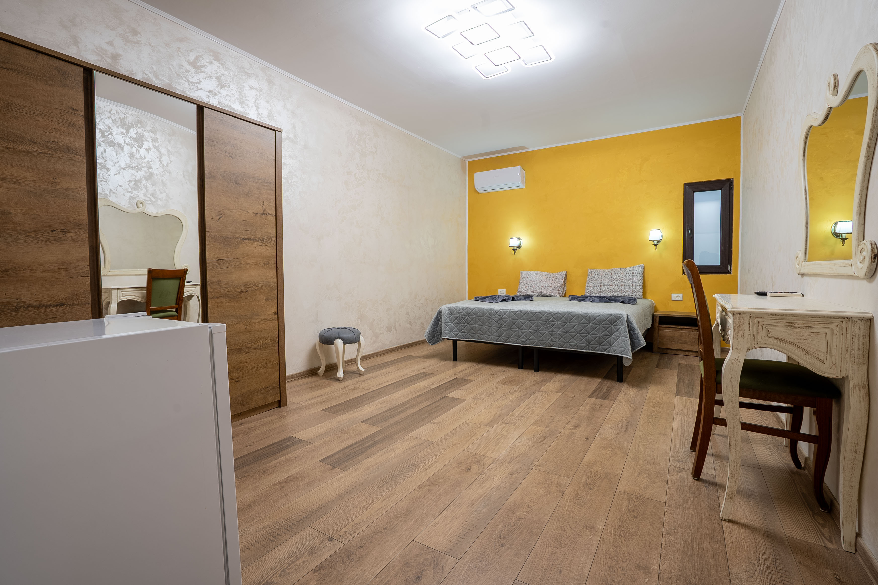 A modern house with large windows and a flat roof, surrounded by greenery against a clear blue sky.