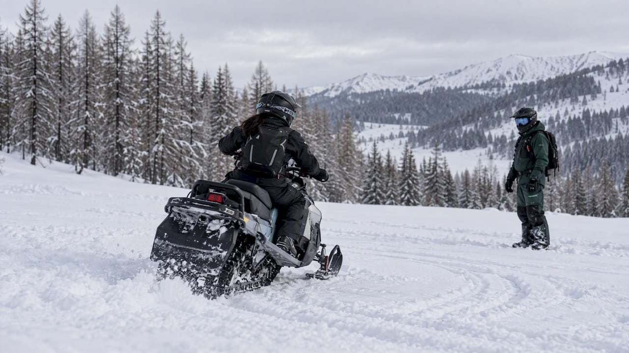 Beginner rider practising a snowmobile turn with an instructor