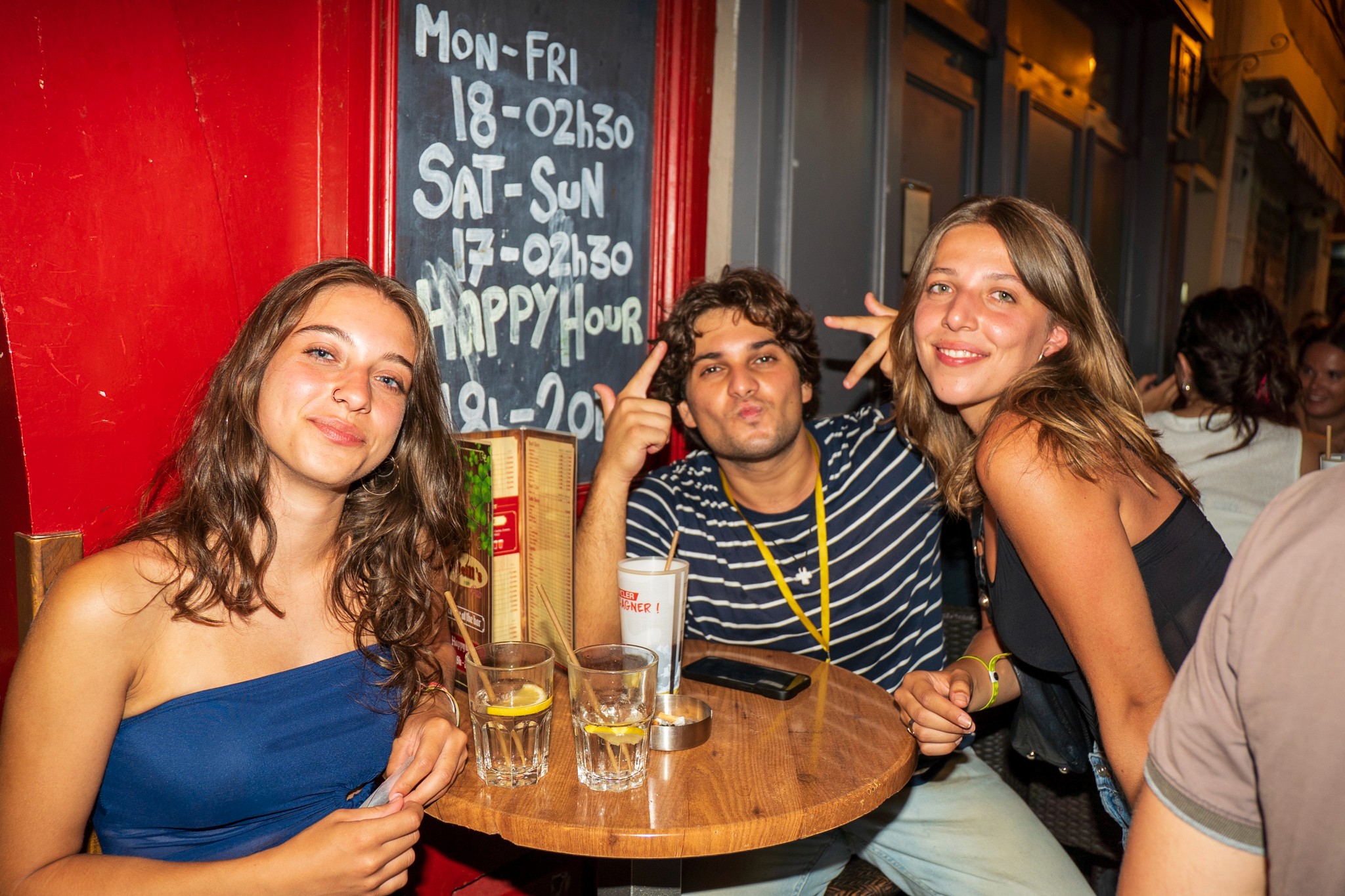 Group of young party travelers enjoying drinks together at a lively bar during a bar crawl in Nice showing relaxed social vibes and the start of a high energy nightlife experience on the French Riviera