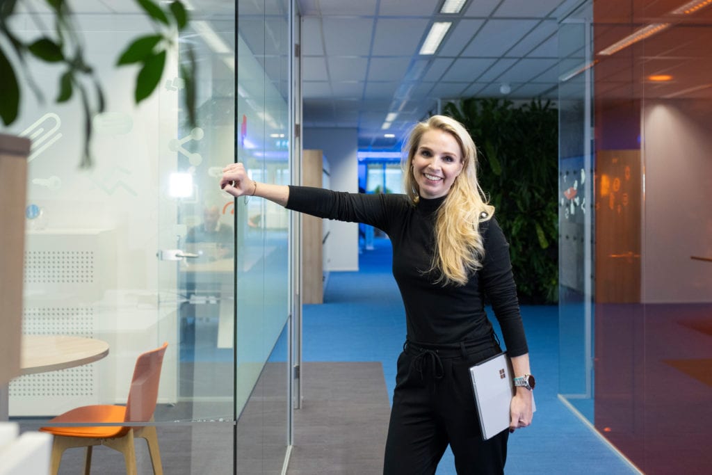 a man with his arms crossed standing in front of a desk