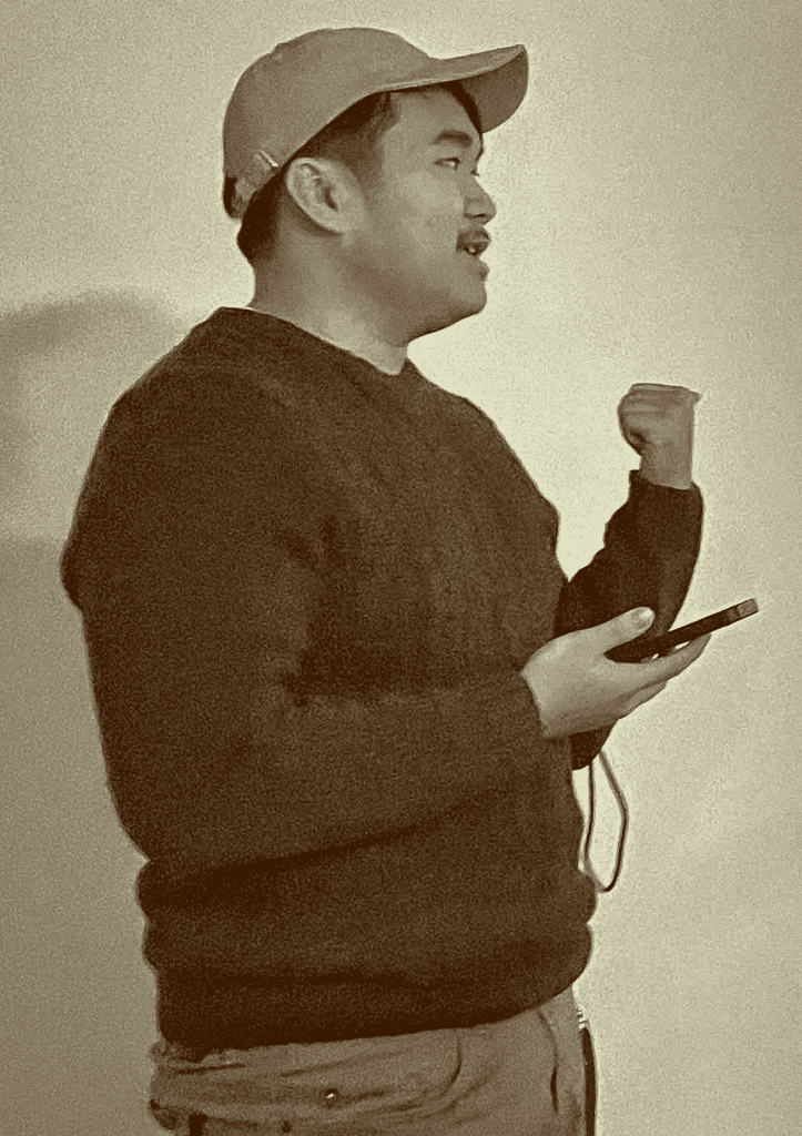 Photo of Evan Saisenesouk holding a Canon XSI Rebel camera in an outdoor garden in Madrid