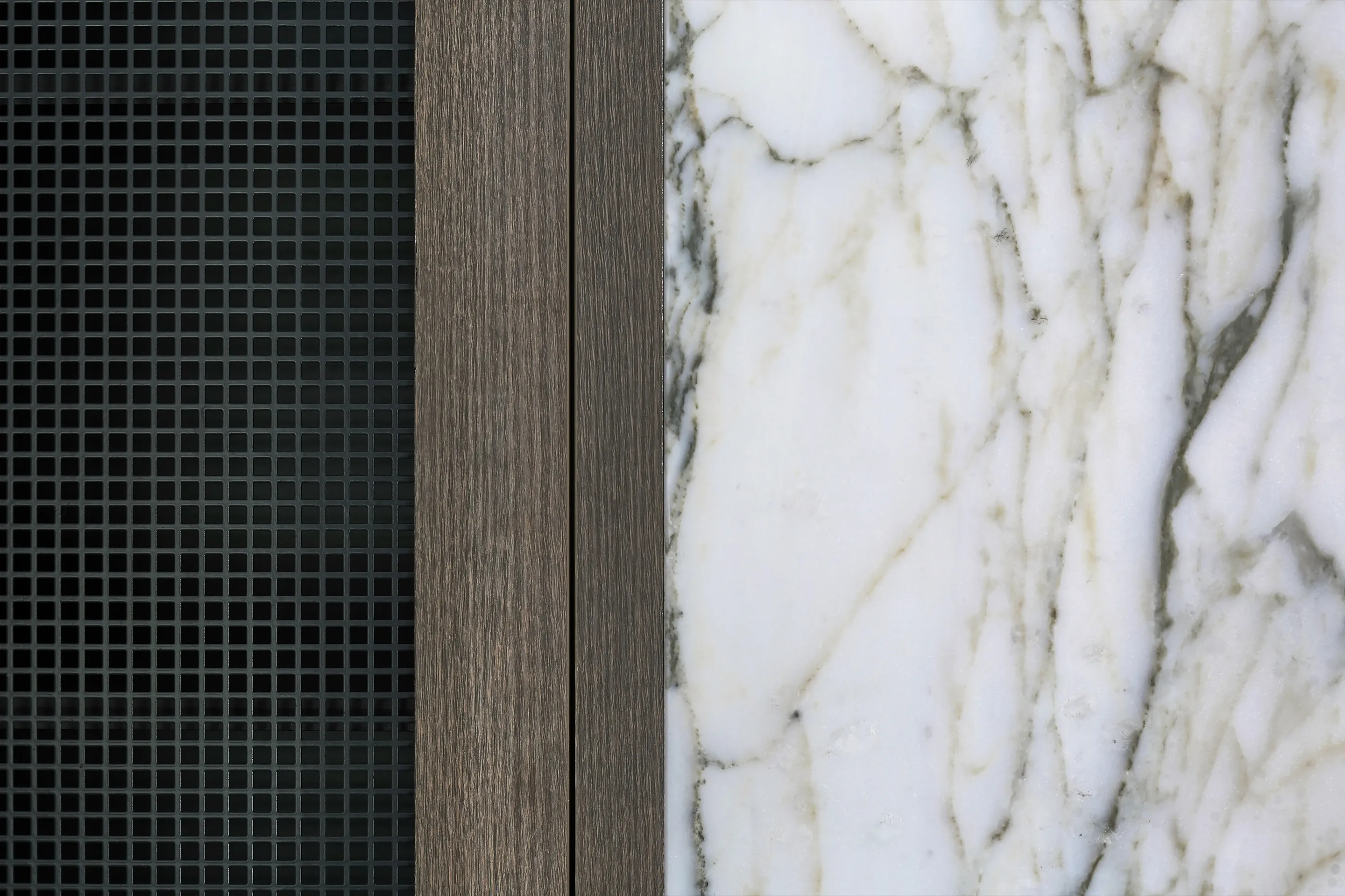 Material detail of the media wall pairing a dark mosaic-tiled panel, a timber-veneer upright and a book-matched Calacatta-veined marble slab