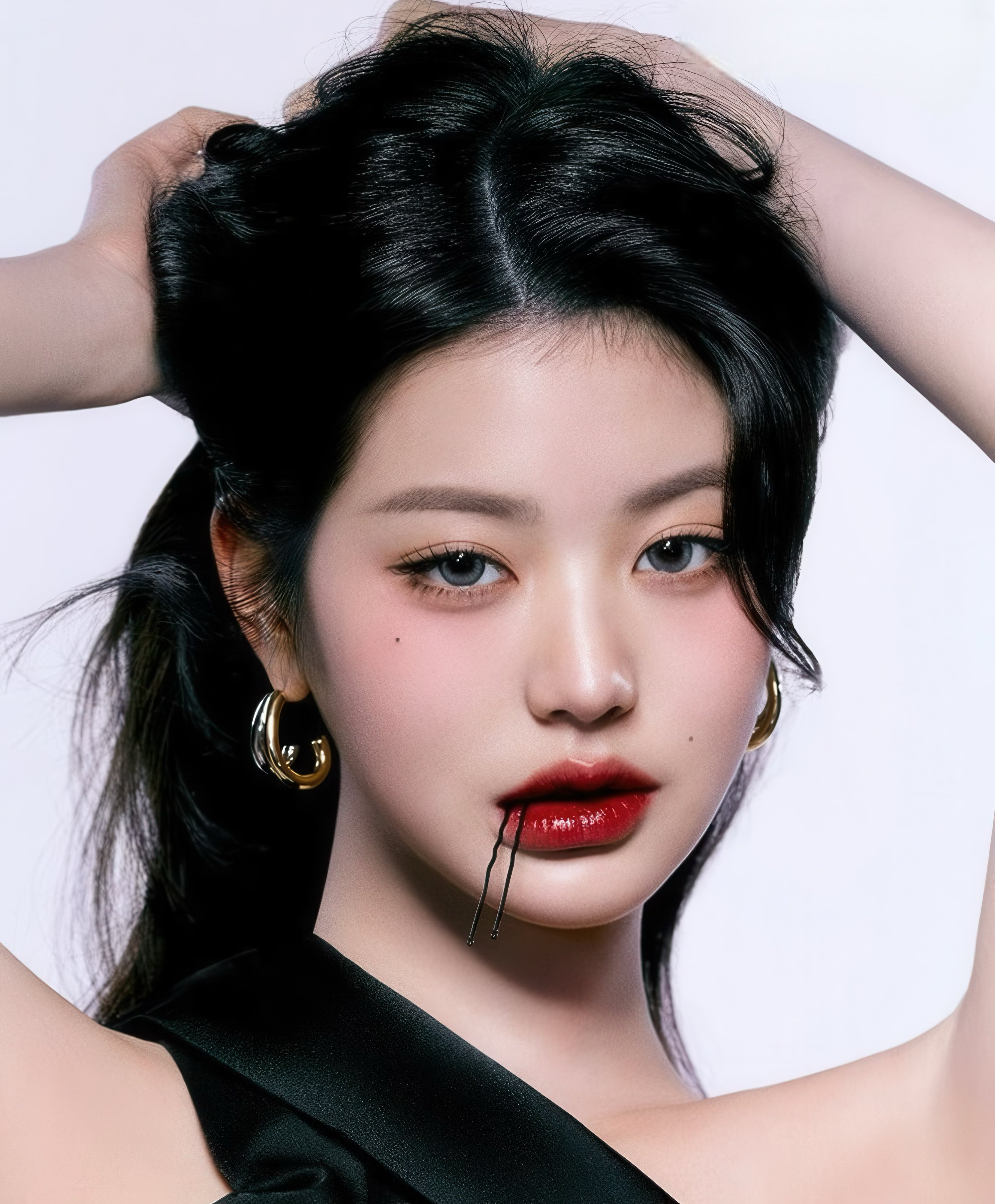 Jang Wonyoung of IVE posing with bold red lips and bobby pins between them, wearing gold hoop earrings, for Kérastase in Vogue Korea.