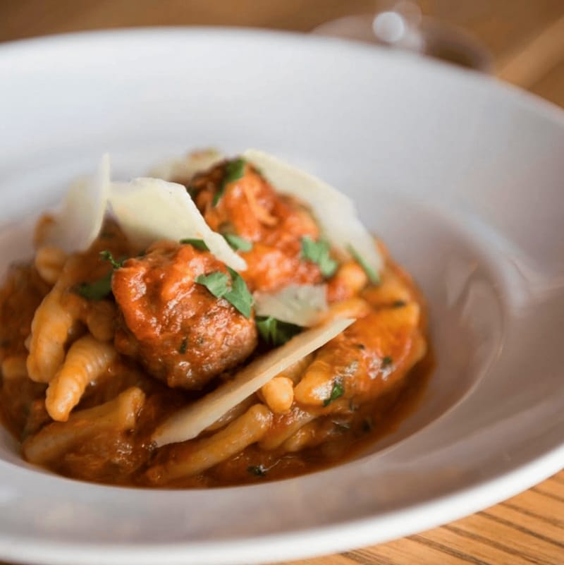 Bowl of cavatelli pasta with baby meatballs, porchetta, and shaved pecorino cheese.
