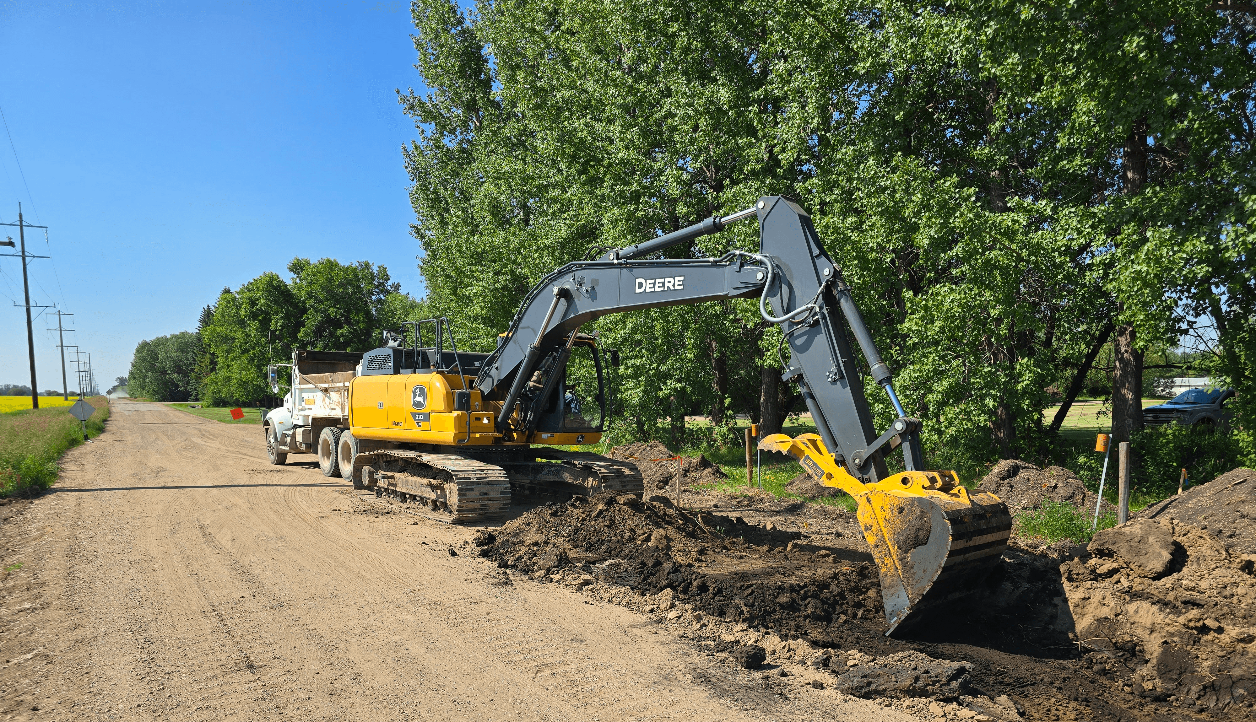 a excavator loading a truck on a county road