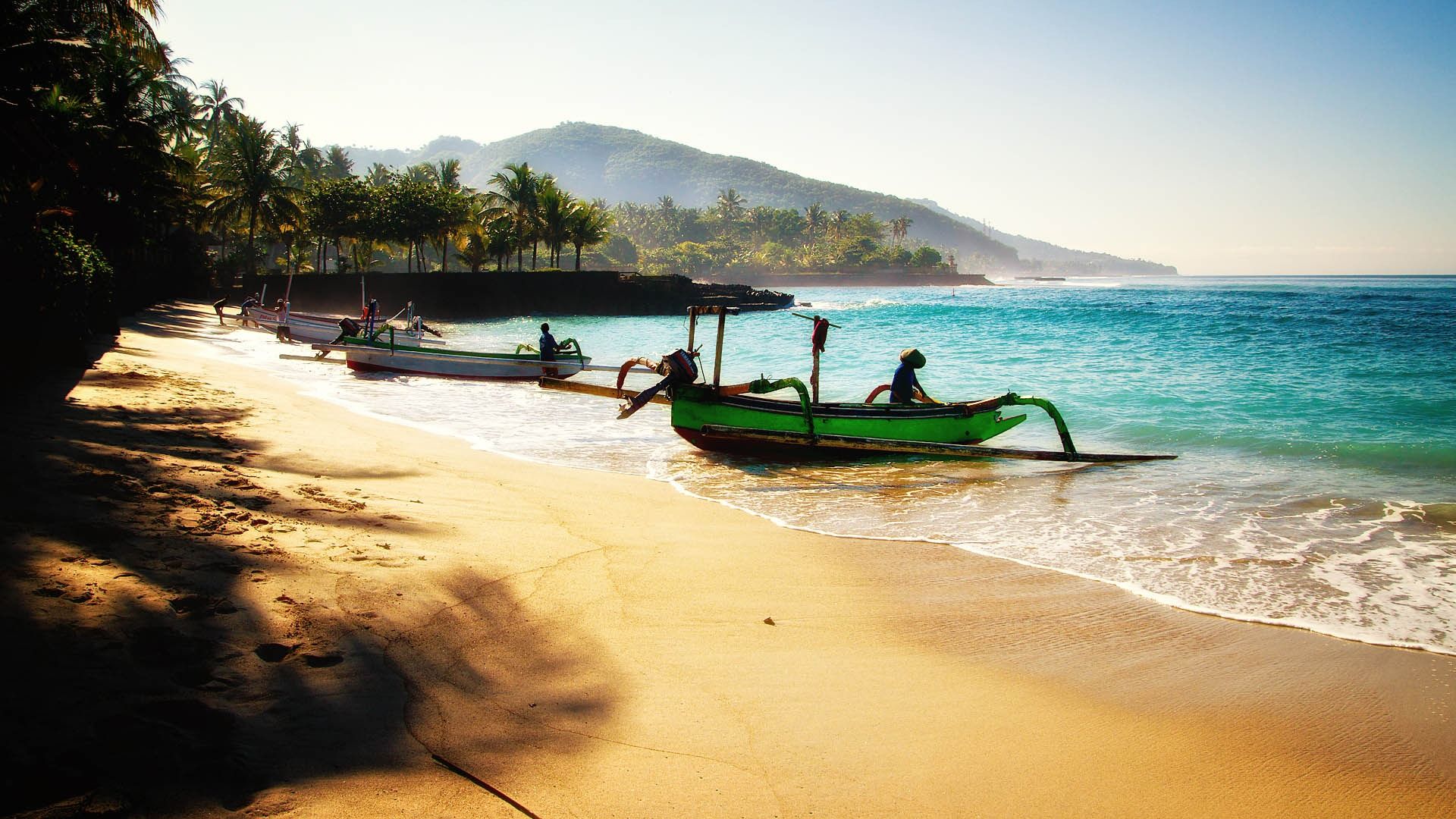 People on three small boats on a beach in Bali