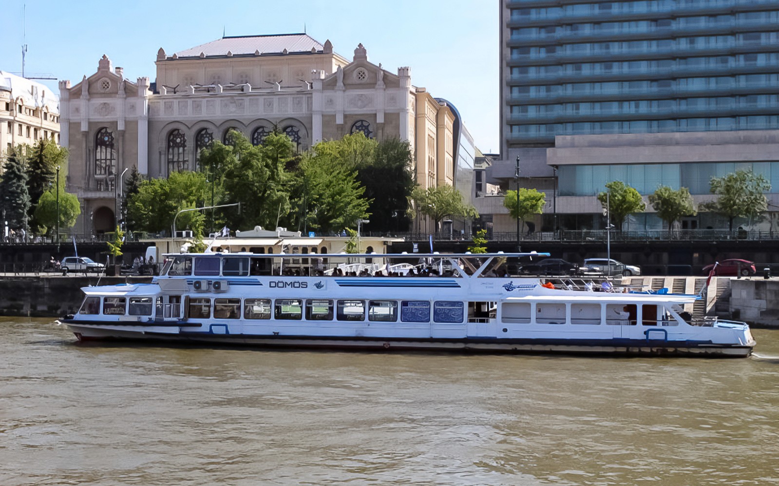Donaukreuzfahrtboot passiert ein historisches Gebäude in Budapest.