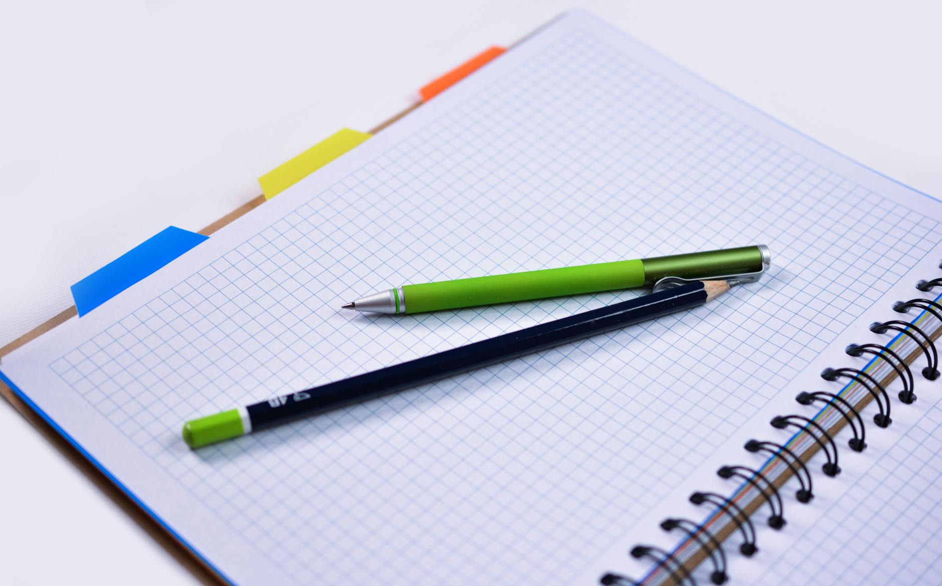 Close-up of a wooden desk featuring a stack of colorful textbooks, a pair of glasses, and a steaming cup of coffee.