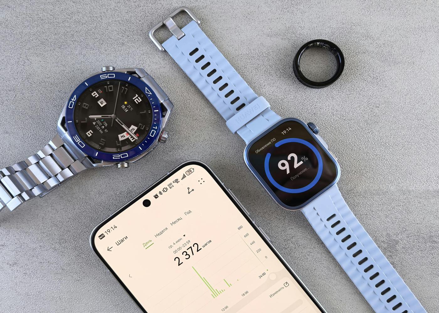 A smart phone next to two smart watches and a smart ring