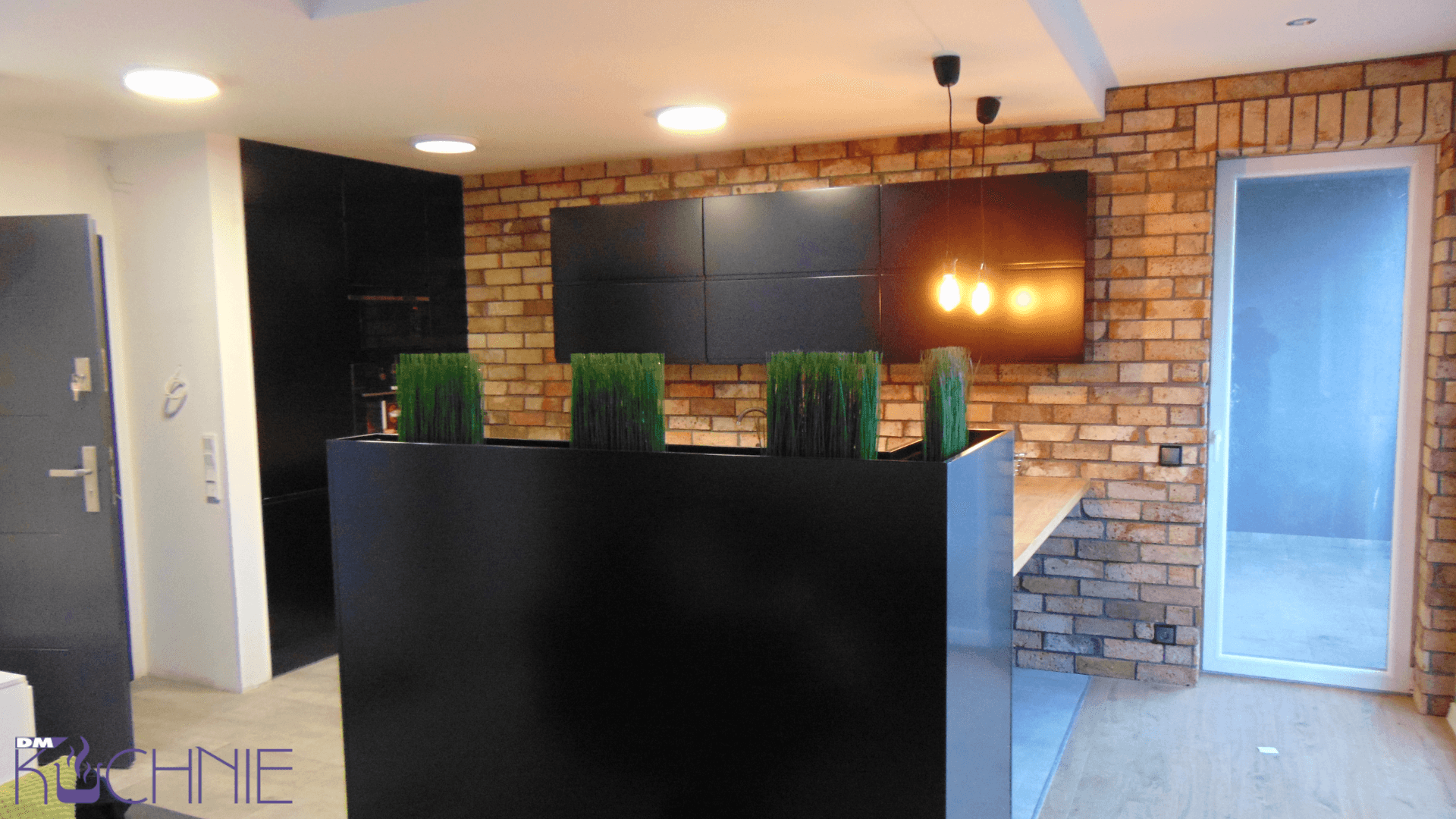 Nowoczesna kuchnia na wymiar w Warszawie z czarną zabudową, ceglaną ścianą i półwyspem