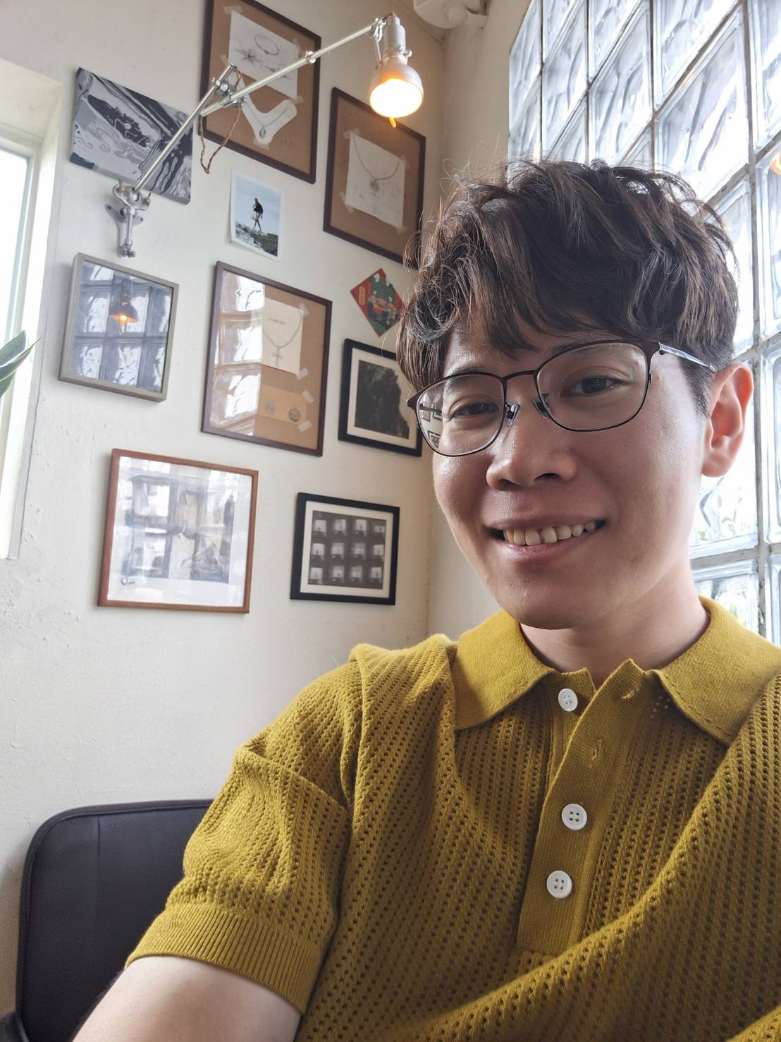 A person with shoulder-length blonde hair wearing a black newsboy cap and a black sweater.