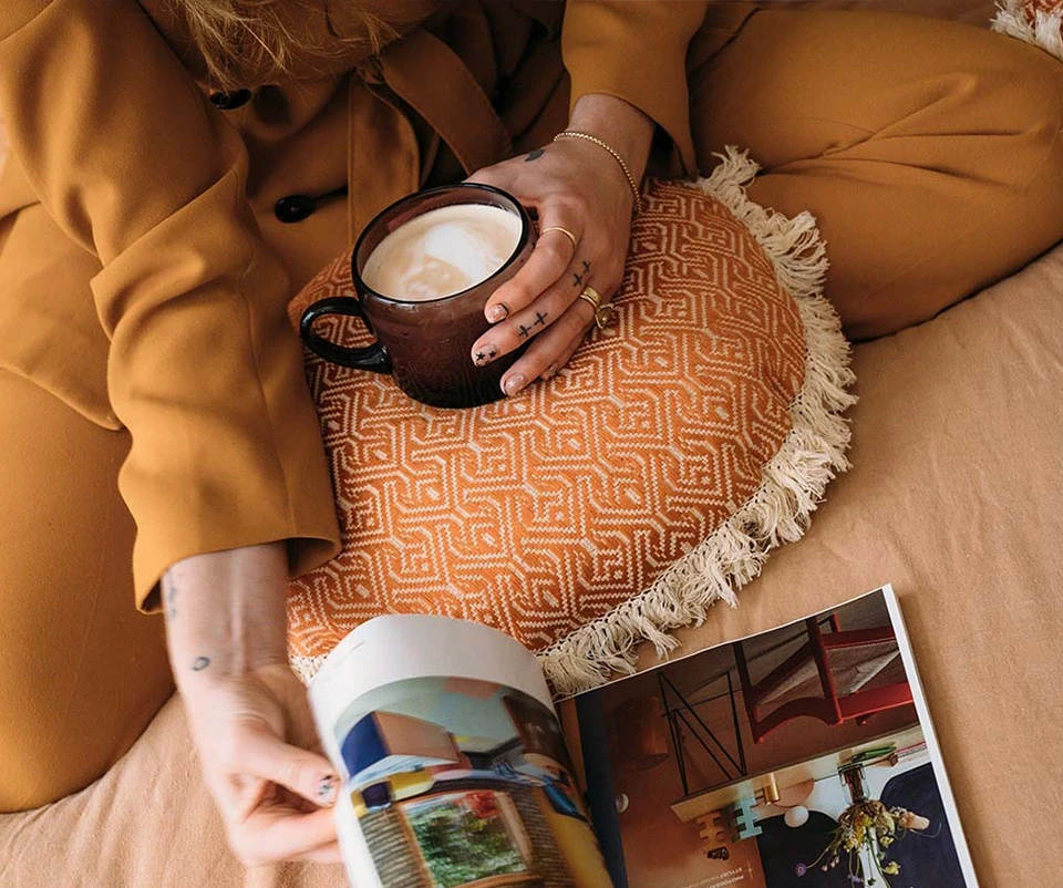 Louisa reading a book while holding a coffee