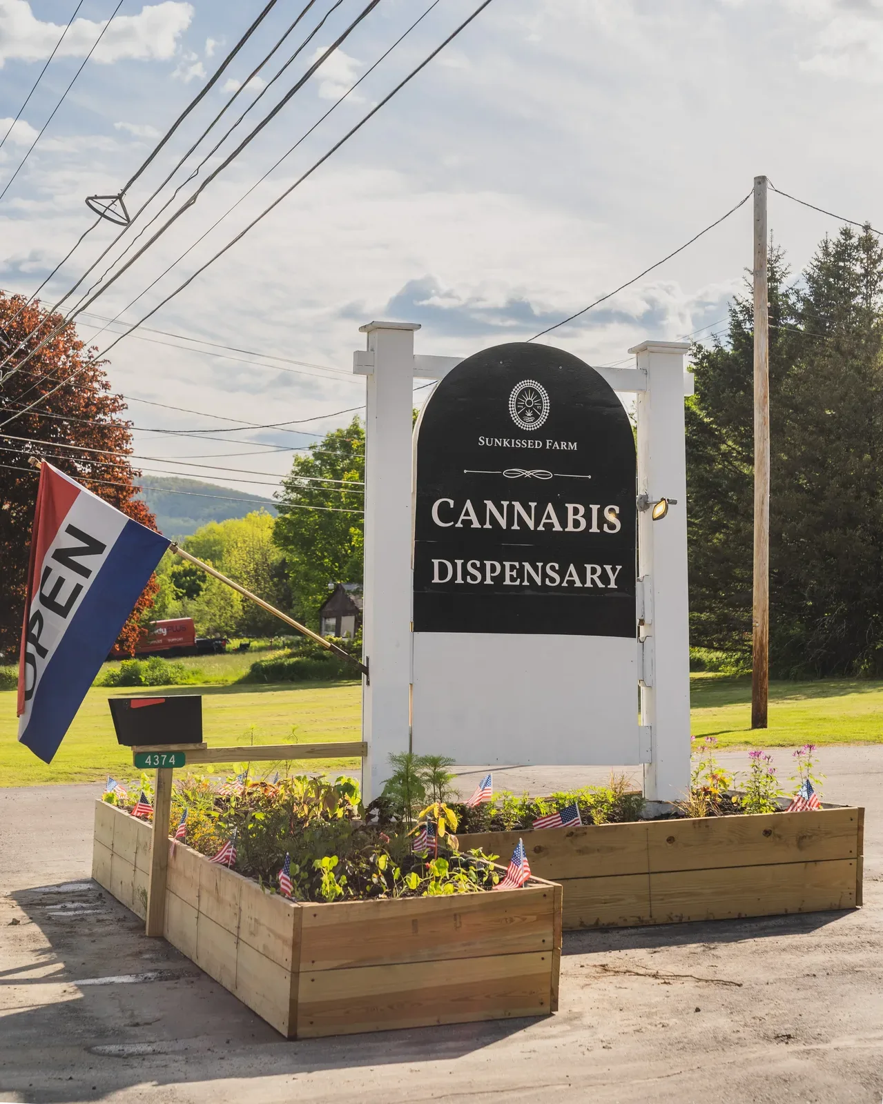 Sunkissed Farm Dispensary sign with open flag and flower beds in Woodstock, Vermont